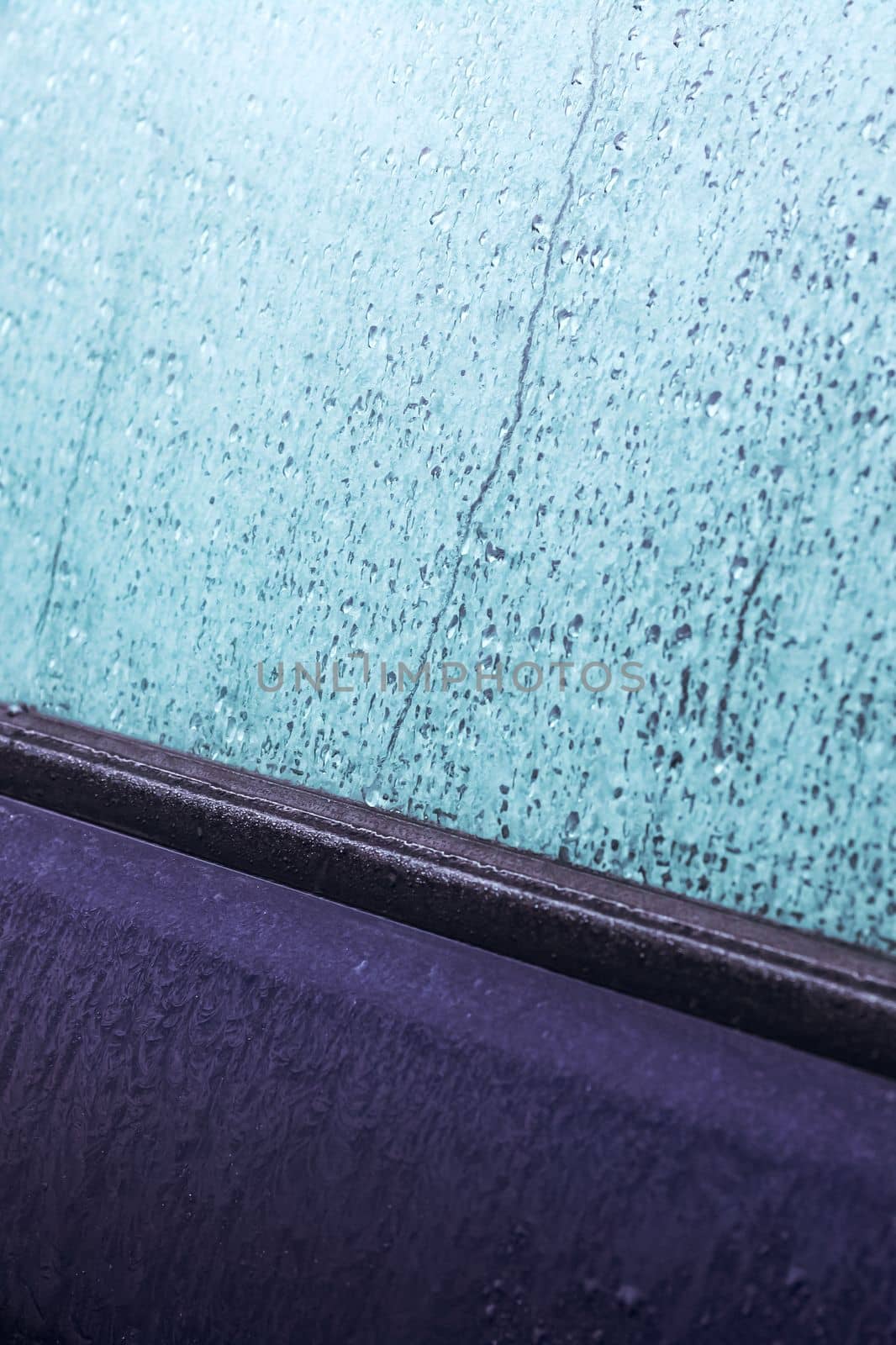 The icy side window of black car close up