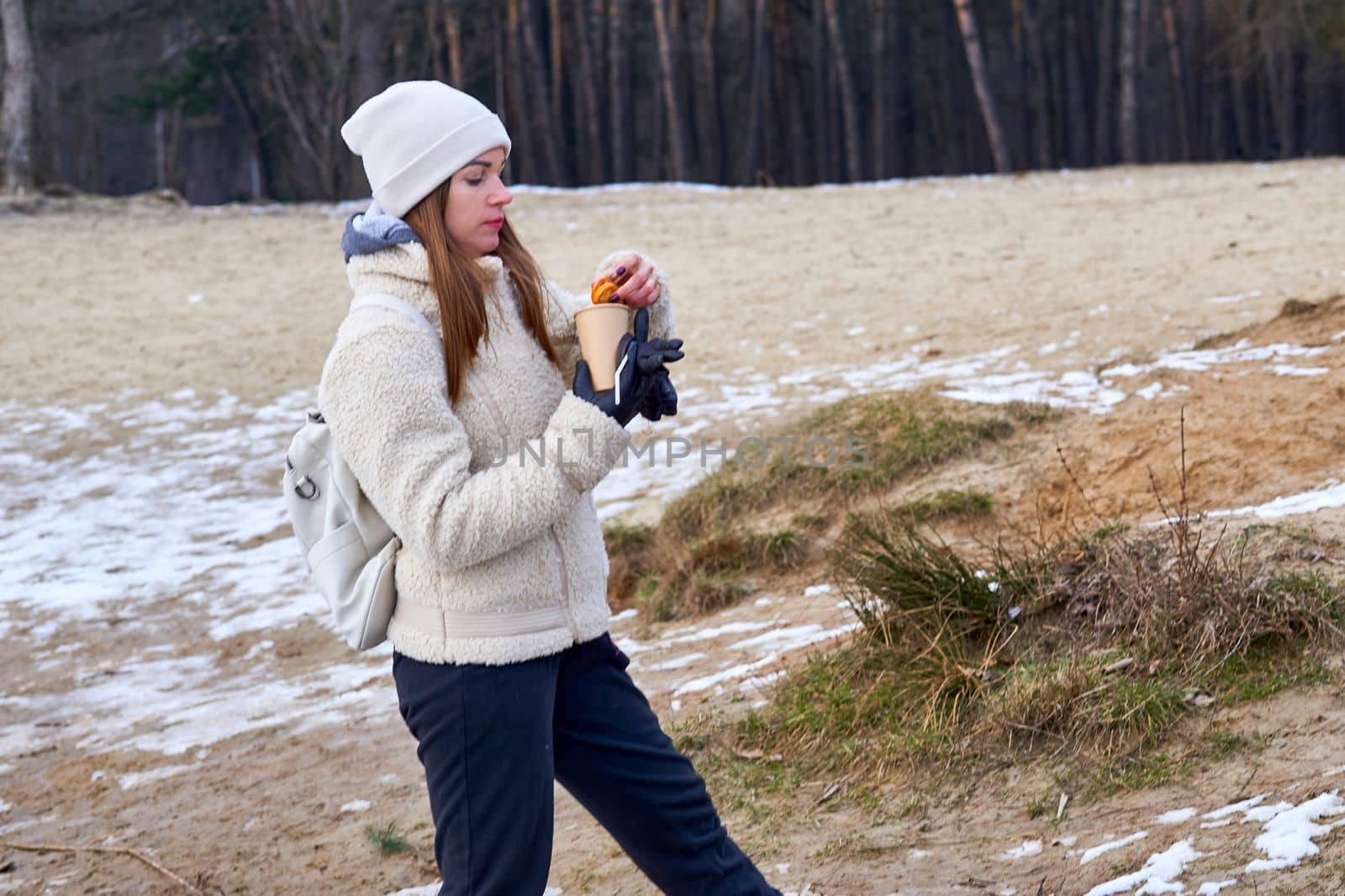 a small amount of food eaten between meals. Young woman hiker having a snack while hiking in spring winter autumn forest.