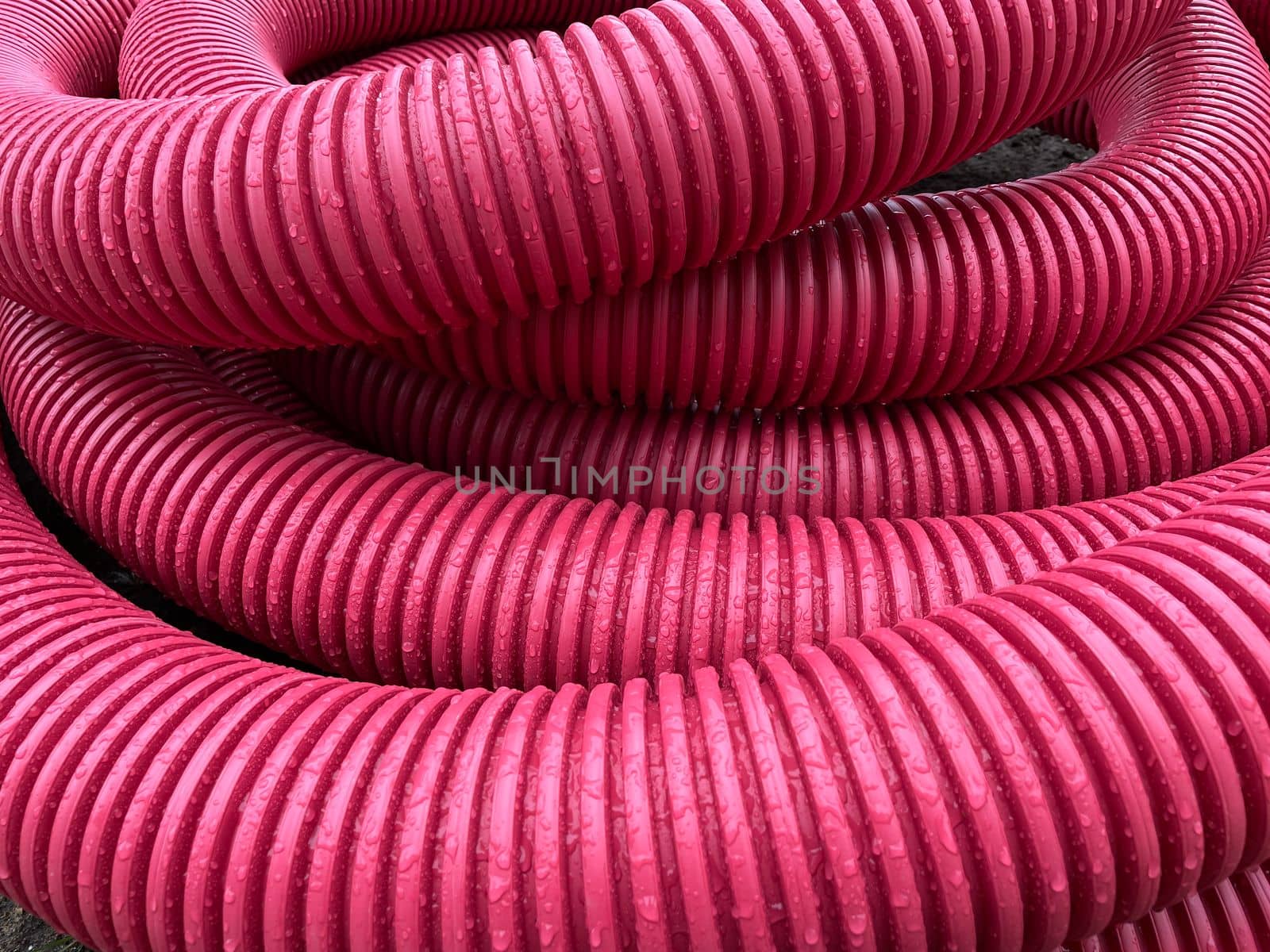 pile of plastic pipes wet from the rain, corrugated burgundy pipes, magenta by KaterinaDalemans