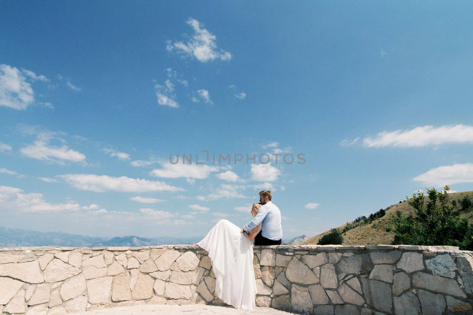 Bride and groom sit hugging on the observation deck. High quality photo