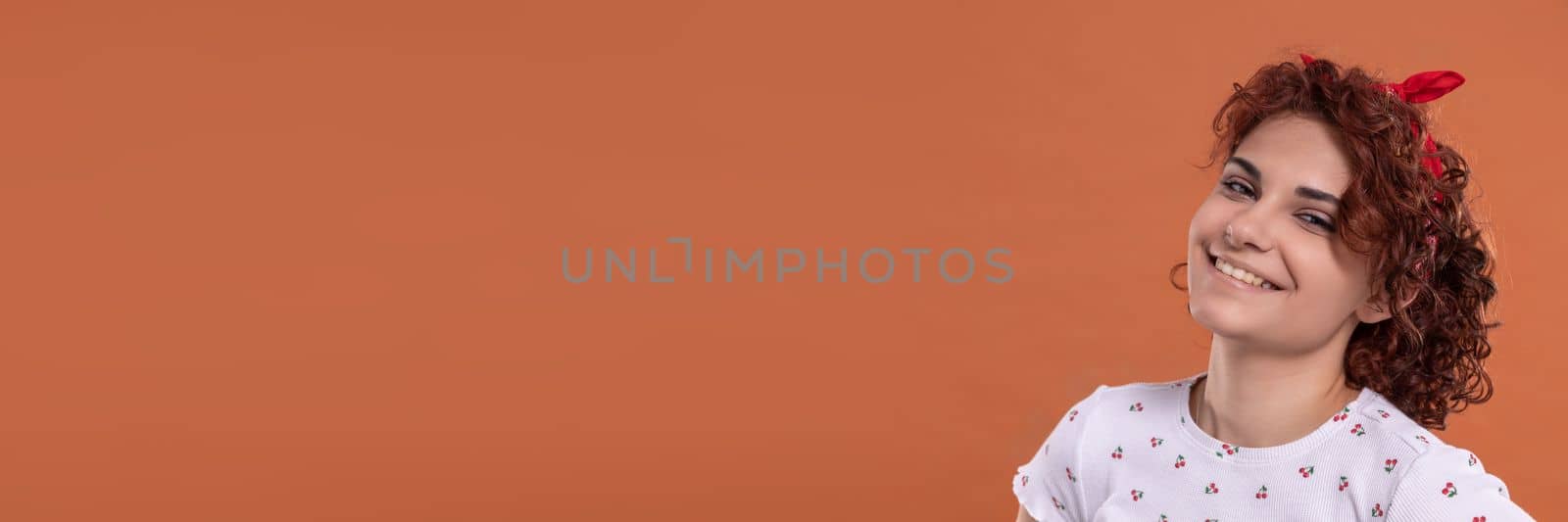 Panoramic frame of young girl. Young girl with a smile on her face. Uniform background in brick-red color. by fotodrobik