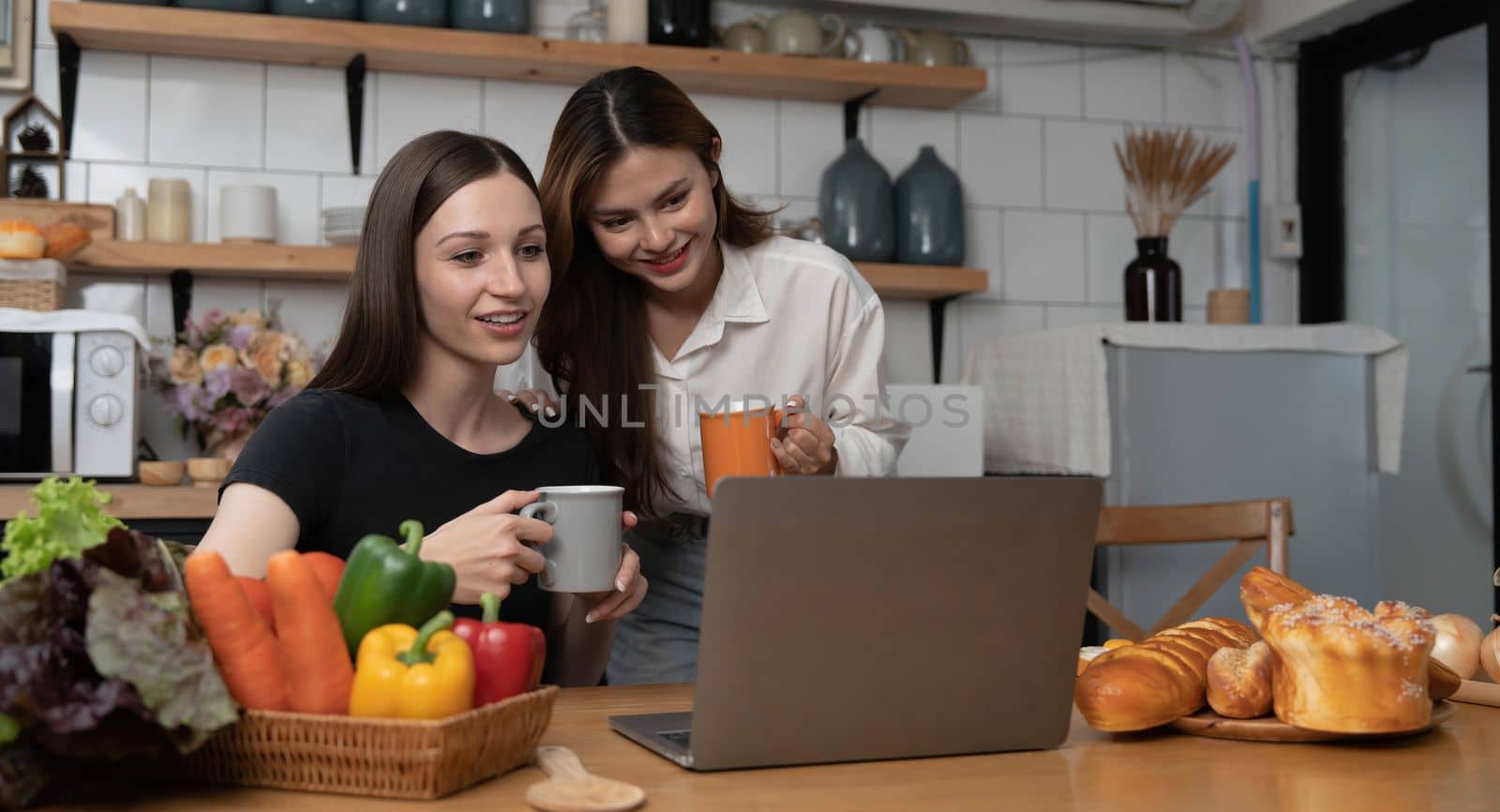 Female and female or LGBT couples are happily cooking bread together with happy smiling face in kitchen at home..