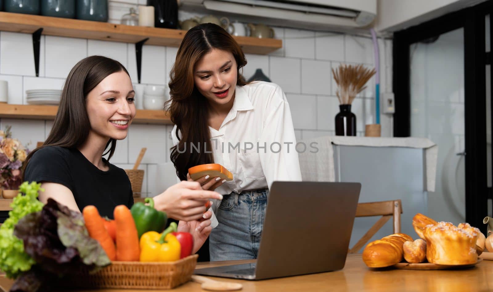 Female and female or LGBT couples are happily cooking bread together with happy smiling face in kitchen at home by wichayada