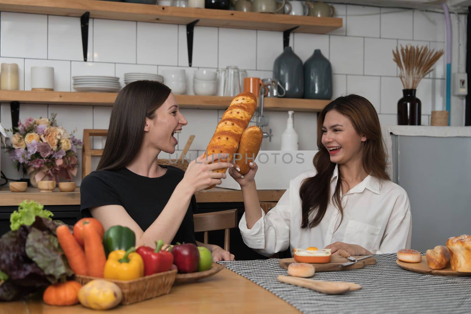 Female and female or LGBT couples are happily cooking bread together with happy smiling face in kitchen at home by wichayada