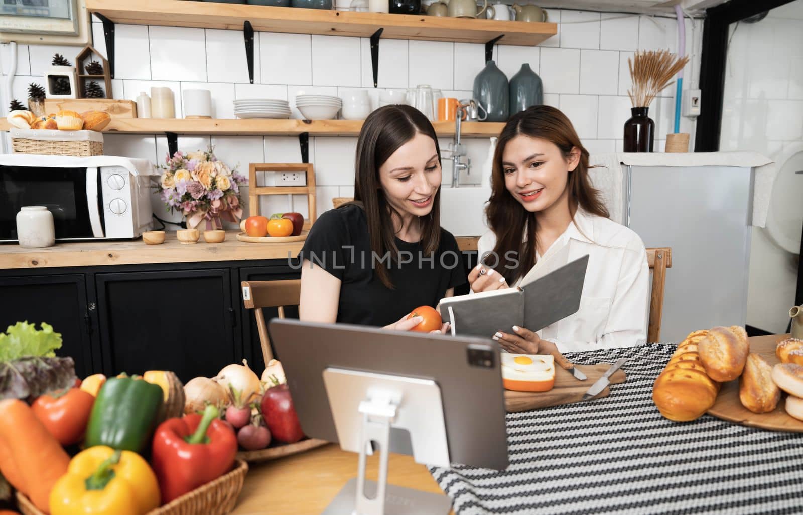 Female and female or LGBT couples are happily cooking bread together with happy smiling face in kitchen at home..