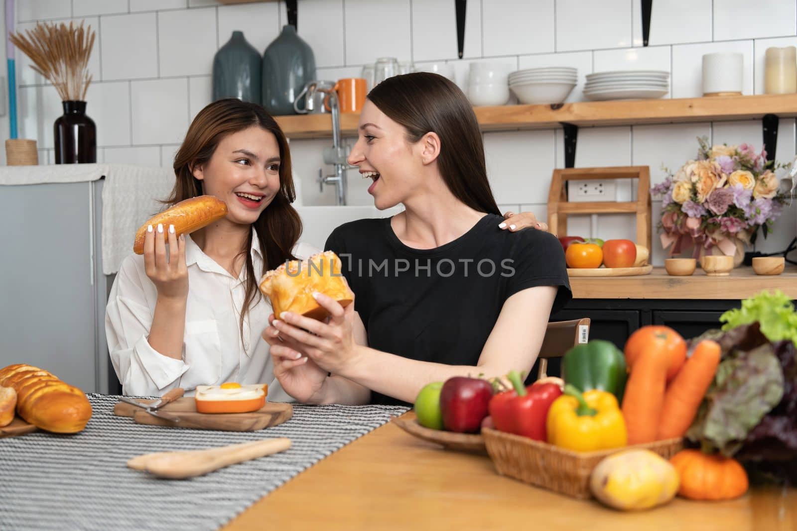 Female and female or LGBT couples are happily cooking bread together with happy smiling face in kitchen at home..