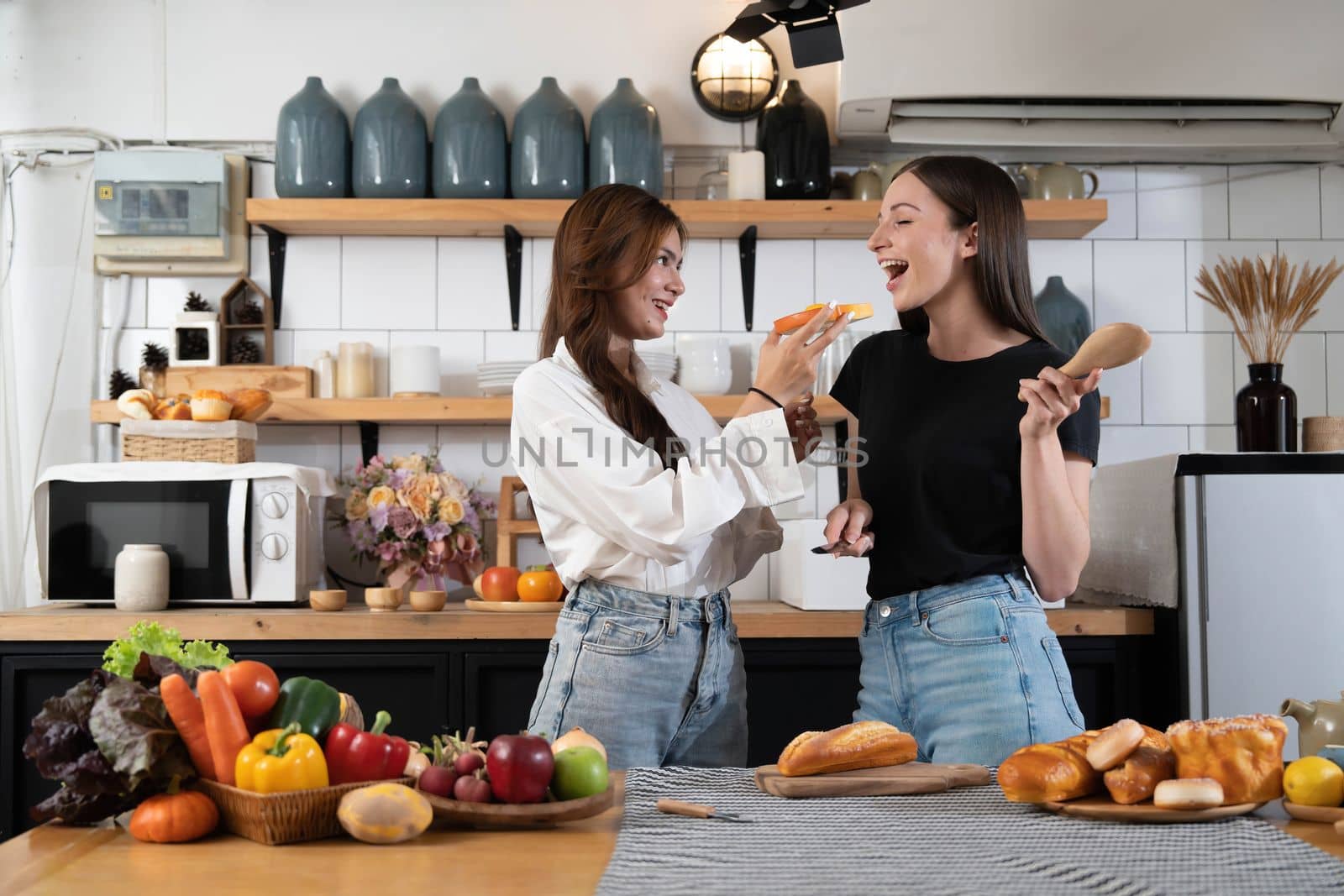 Female and female or LGBT couples are happily cooking bread together with happy smiling face in kitchen at home by wichayada