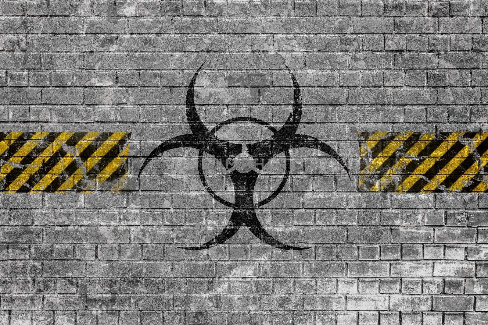 Faded biohazard sign with yellow-black lines on old brick wall with scratches and peeling paint