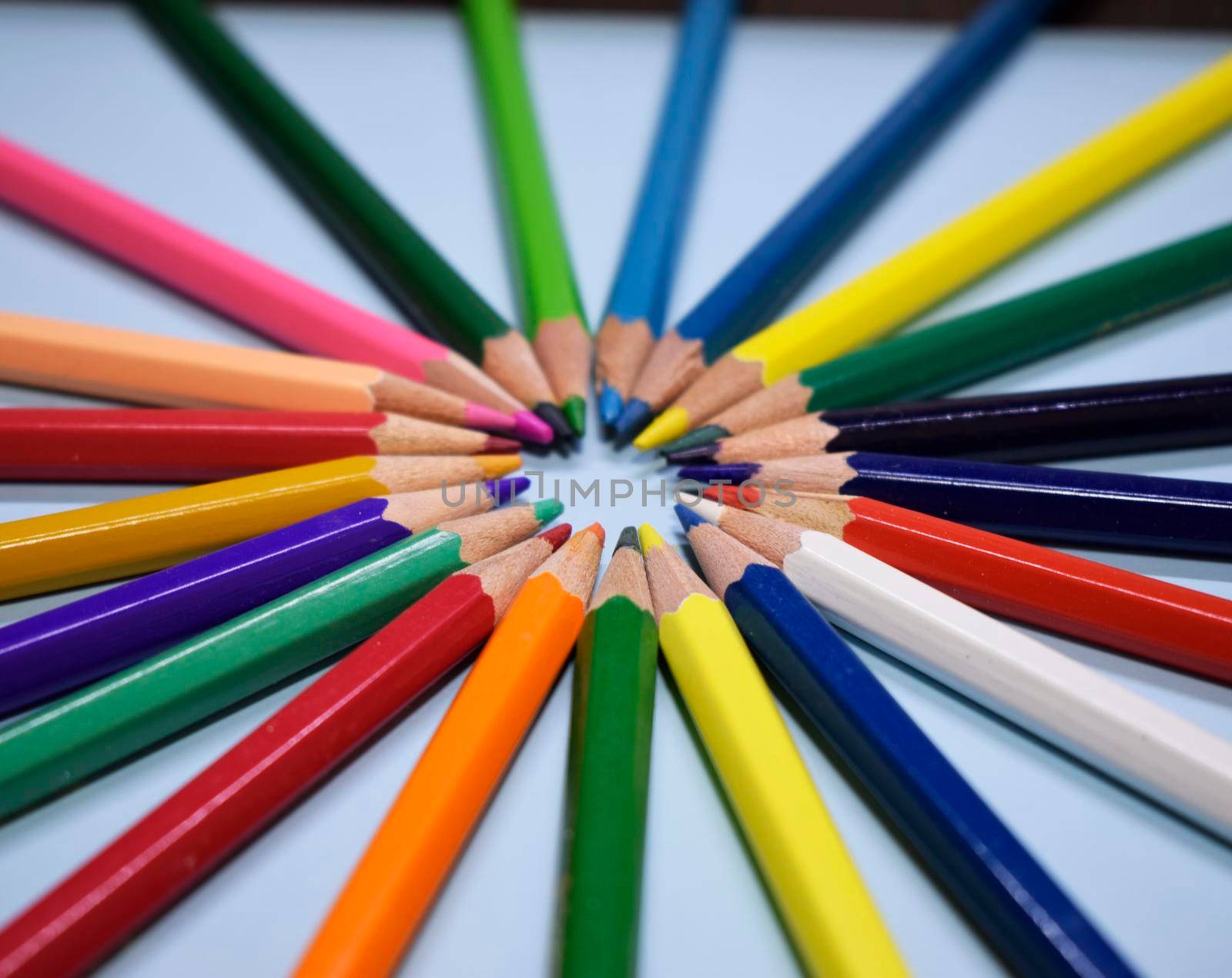 Closeup colorful pencil on blue paper background. Macro of a group pencils in a circle. Business concept, teamwork, united group