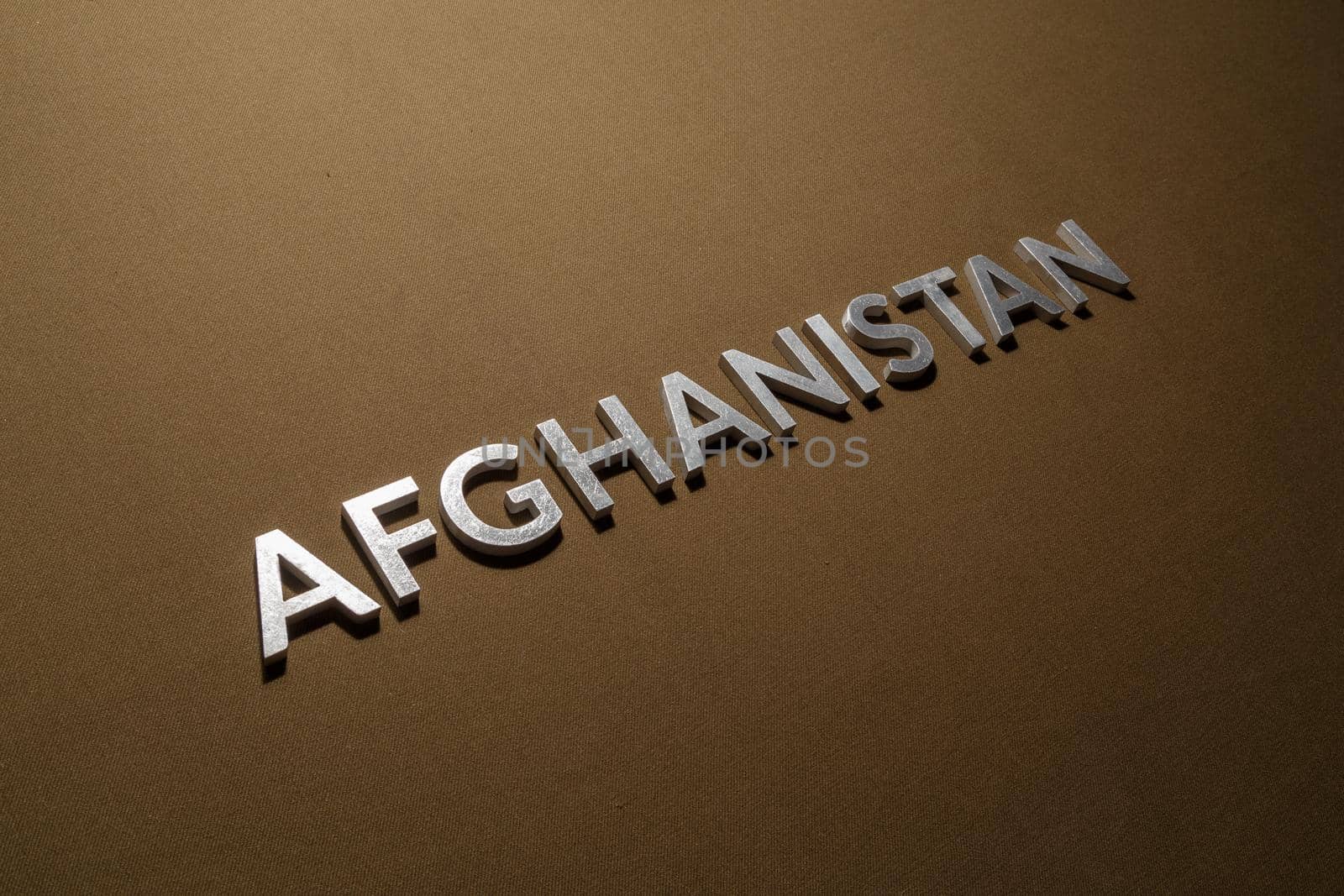 the word afghanistan laid with silver metal letters on tan khaki canvas fabric
