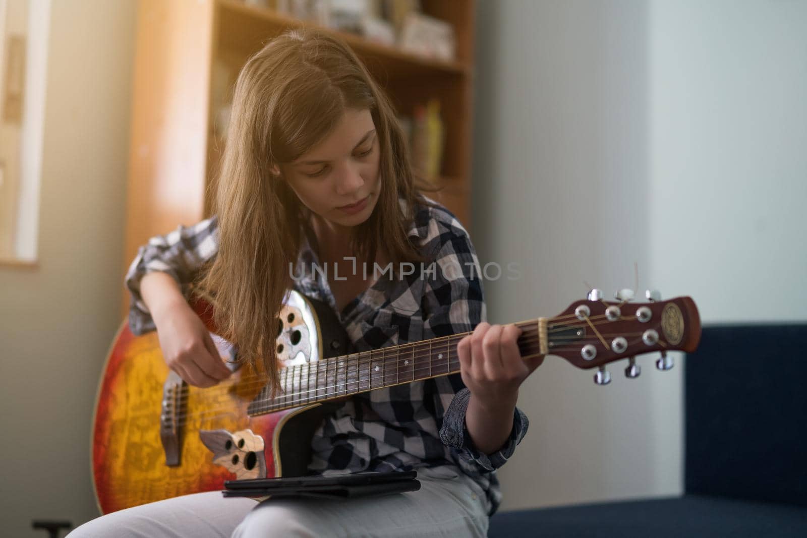 Teenage girl is playing guitar at home.