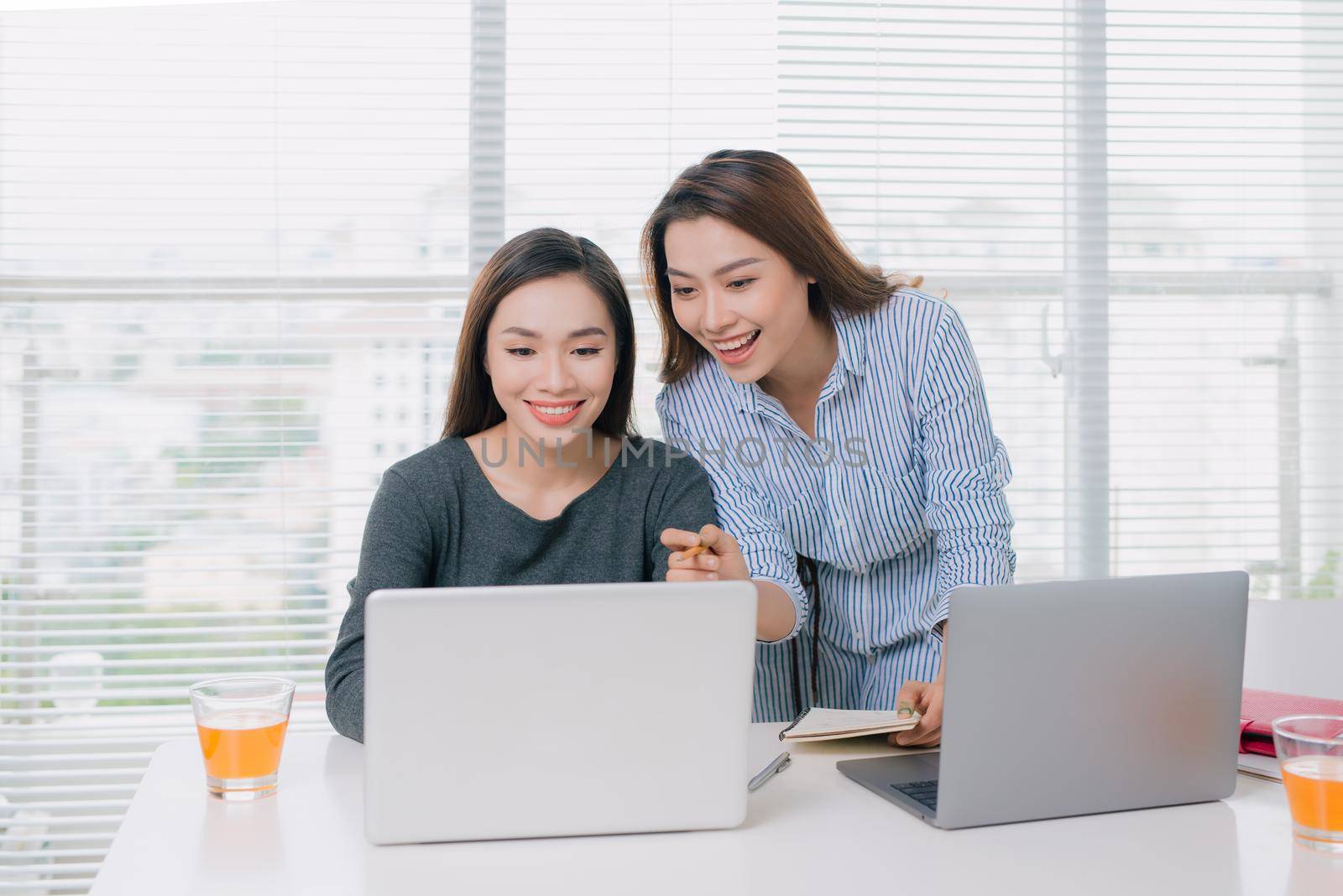 Two female businesswoman friends talking at office by makidotvn