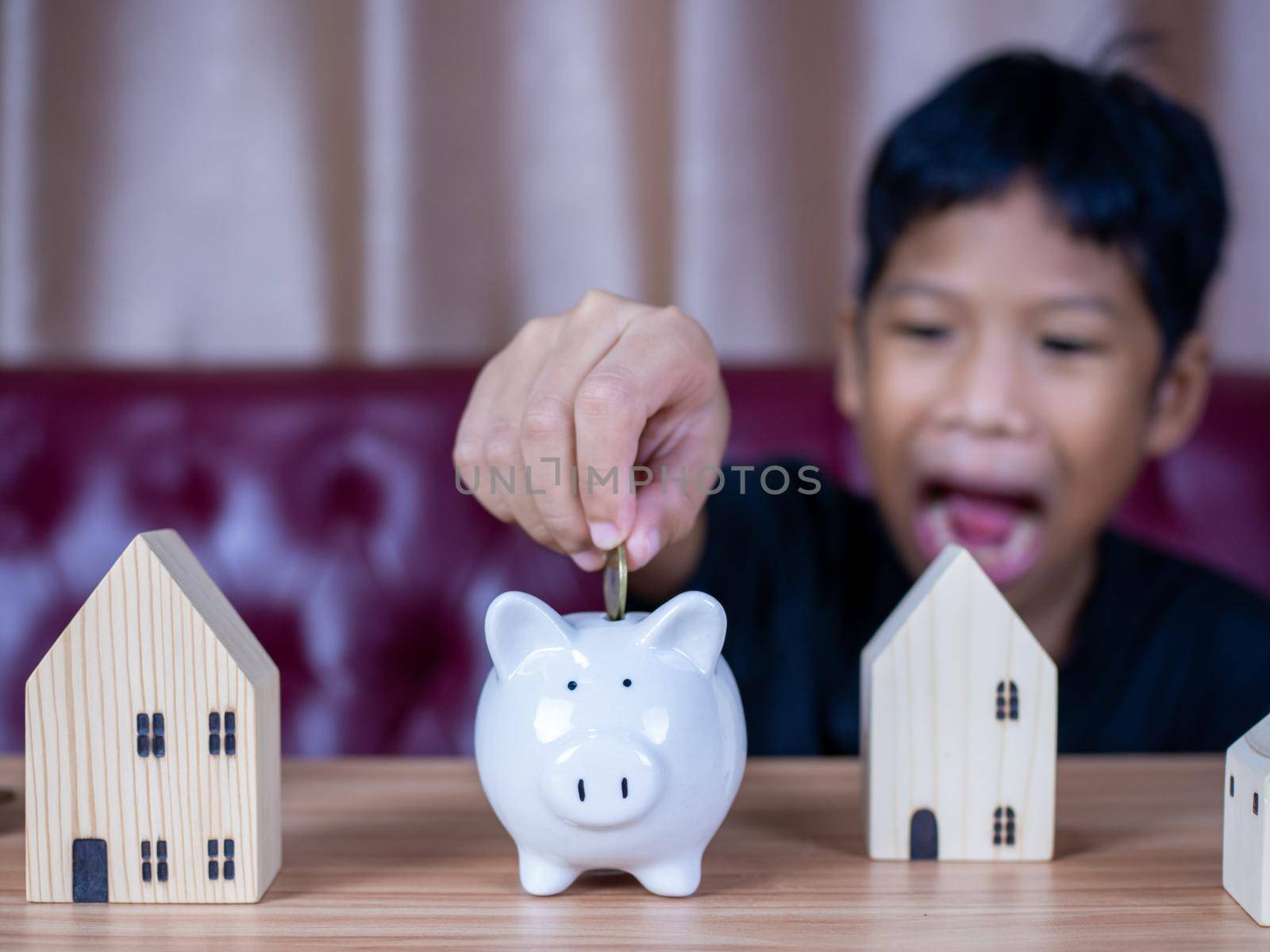 Boy saving money in a white pig piggy bank.Saving concept. Saving for the future. by Unimages2527