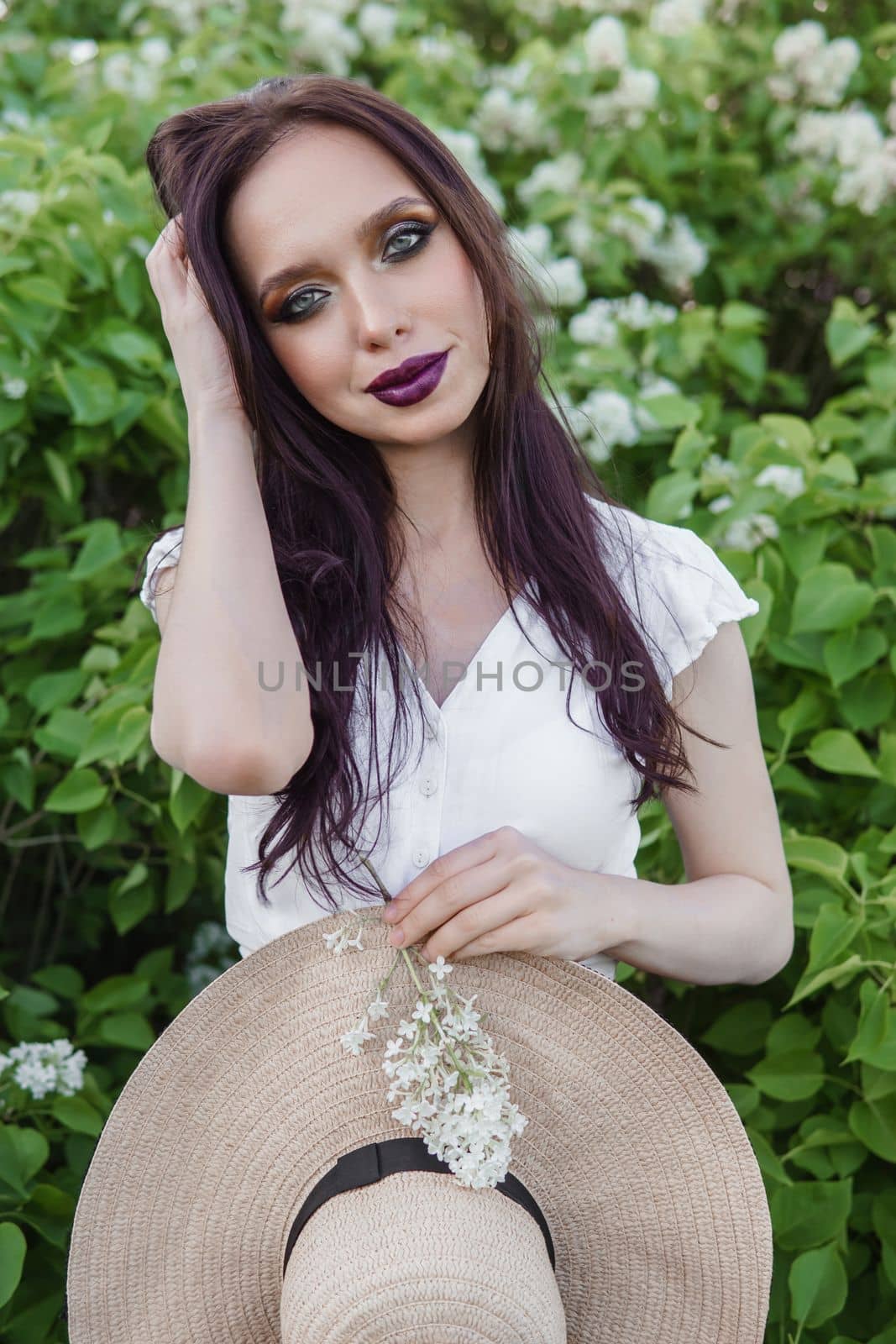 A fashionable girl with dark hair, a spring portrait in lilac tones in summer. Bright professional makeup