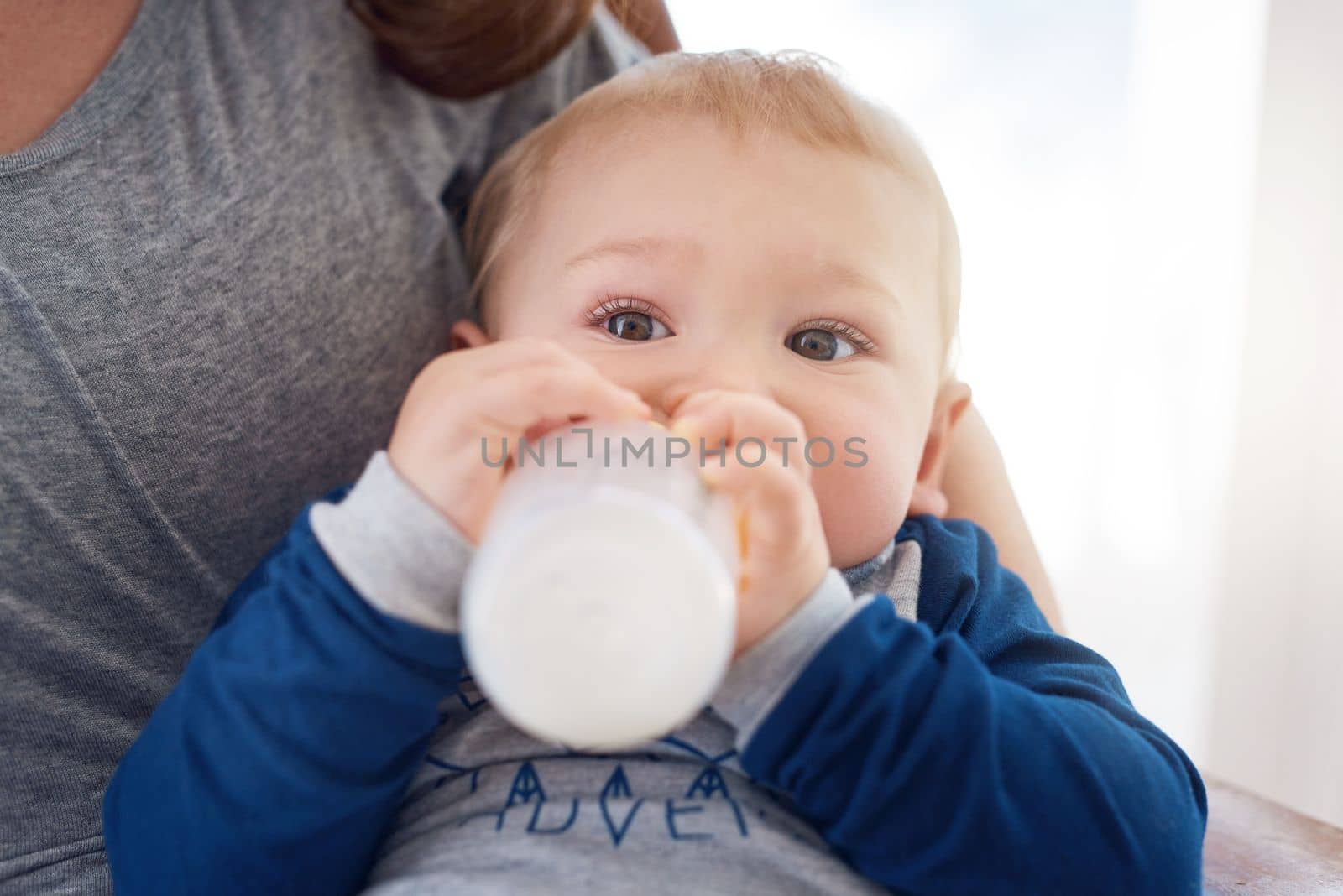 He loves his bottle. a mother feeding her baby boy at home