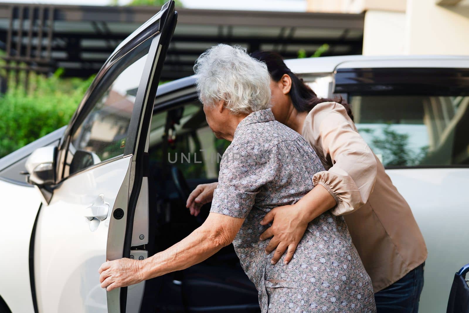 Caregiver help Asian elderly woman disability patient get in her car, medical concept. by sweettomato