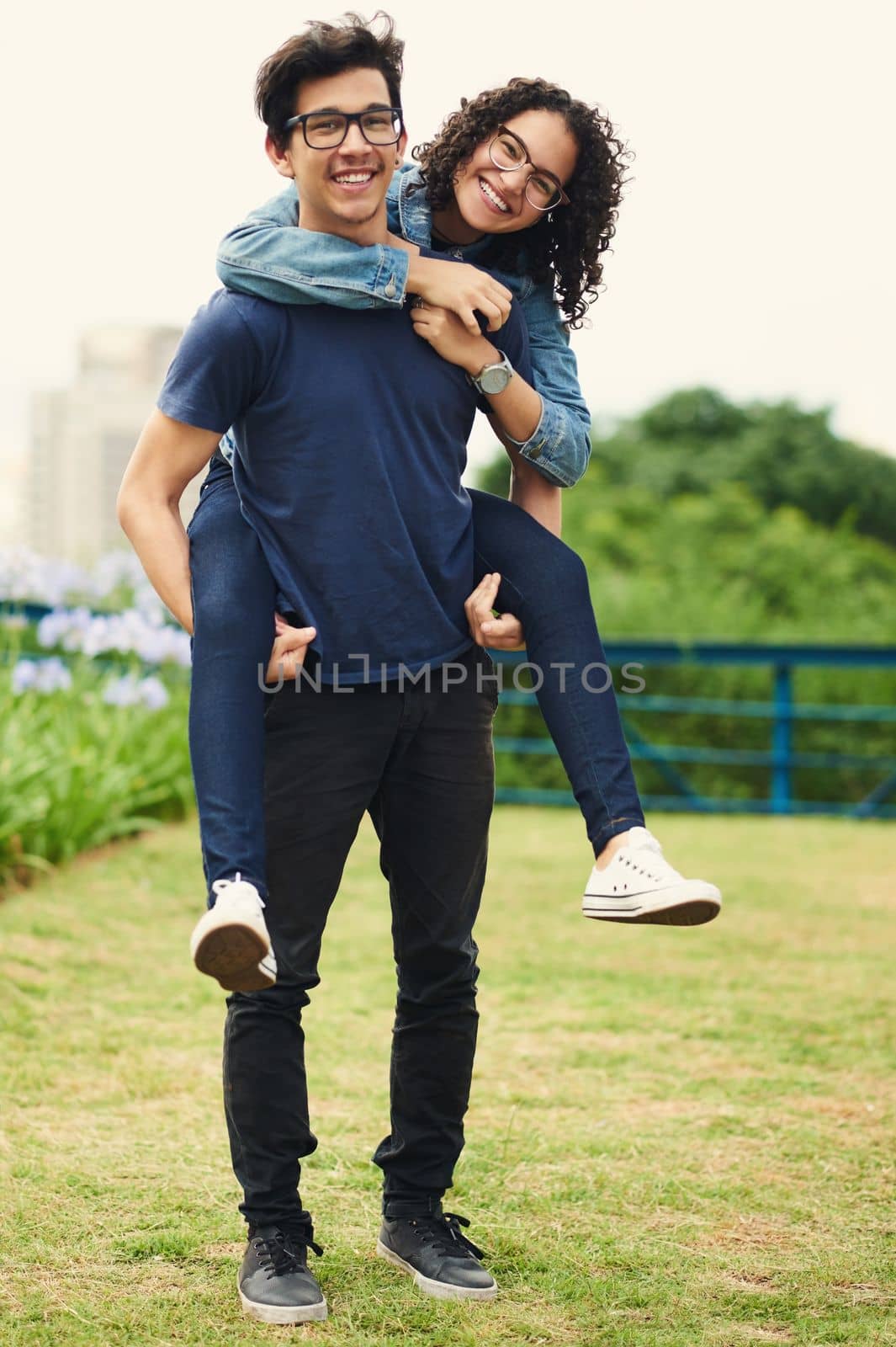 We are young therefor we are playful in love. a teenage girl being piggybacked by her teenage boyfriend outdoors. by YuriArcurs