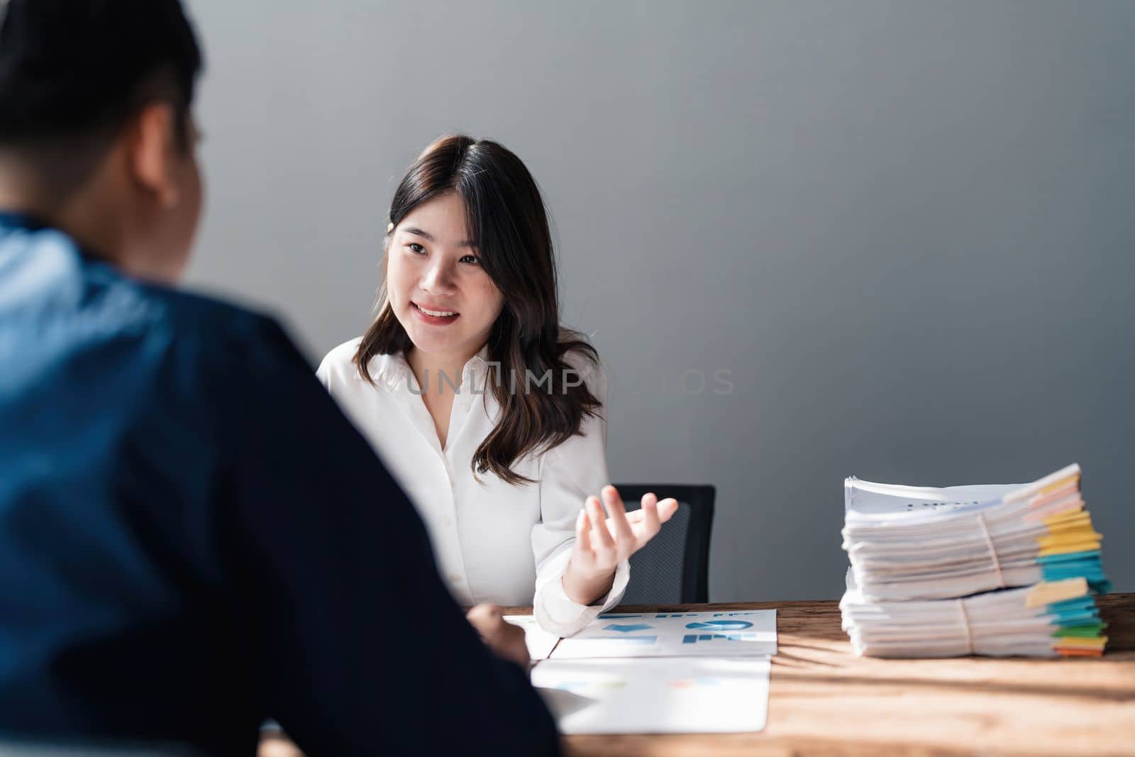 Two business people talk project strategy at office meeting room. Businessman discuss project planning with colleague at modern workplace while having conversation and advice on financial data report. by wichayada