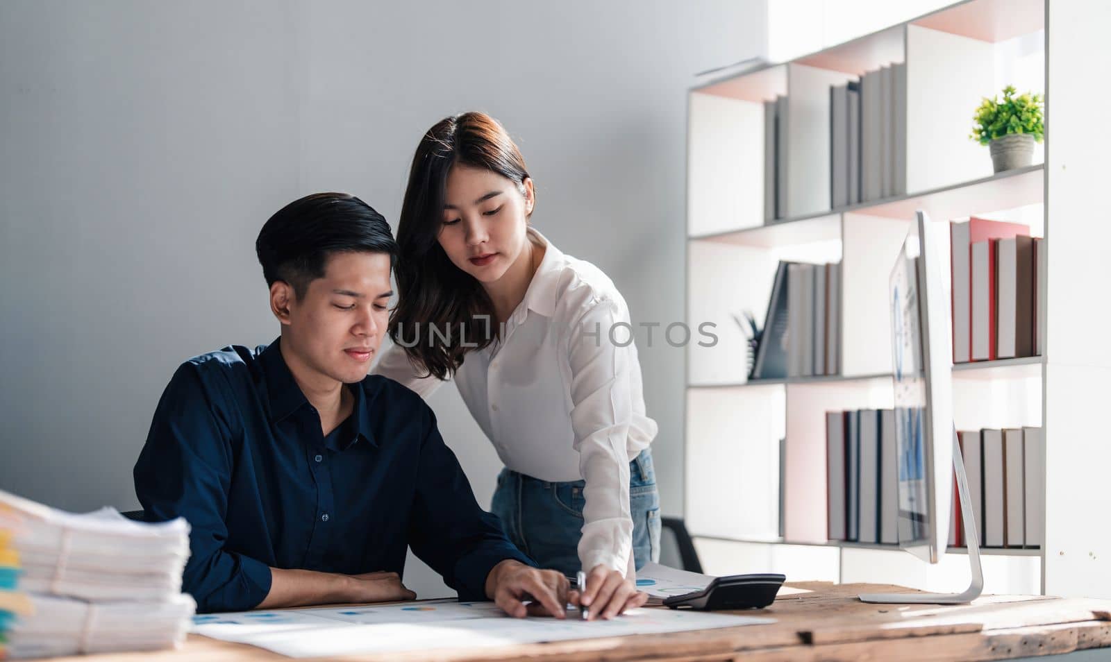 Two business people talk project strategy at office meeting room. Businessman discuss project planning with colleague at modern workplace while having conversation and advice on financial data report. by wichayada