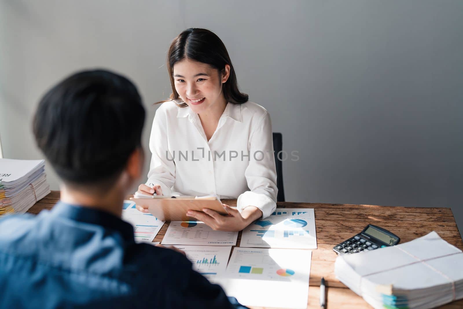 Two business people talk project strategy at office meeting room. Businessman discuss project planning with colleague at modern workplace while having conversation and advice on financial data report...