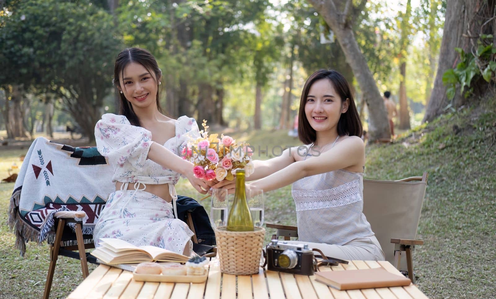 Gorgeous Asian woman giving a beautiful roses bouquet to her friend, having a special moment together in the park. female couple, lesbian, bestfriend, besties.