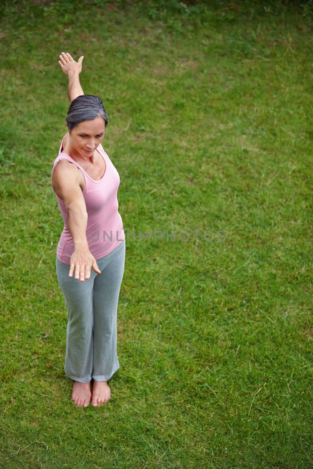 Focussing on her posture. High angle shot of an attractive mature woman doing yoga outdoors