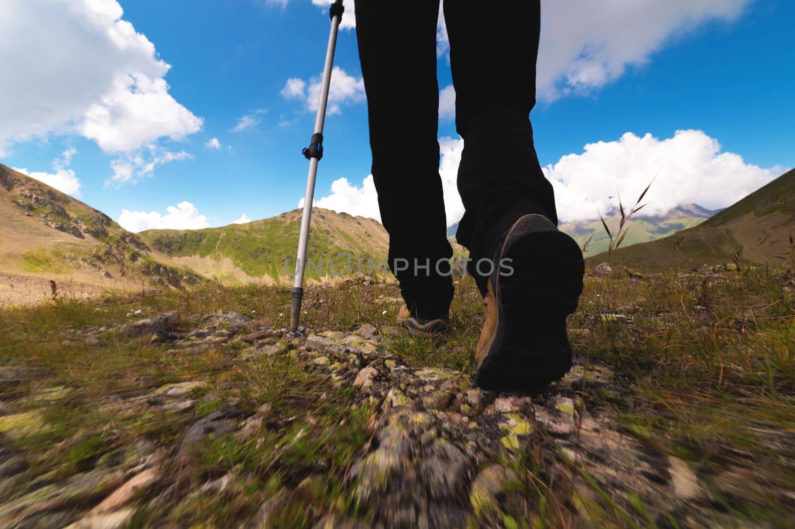 legs of an adult in boots for walking in the mountains. travel and hiking concept. ground view from below, quick step.