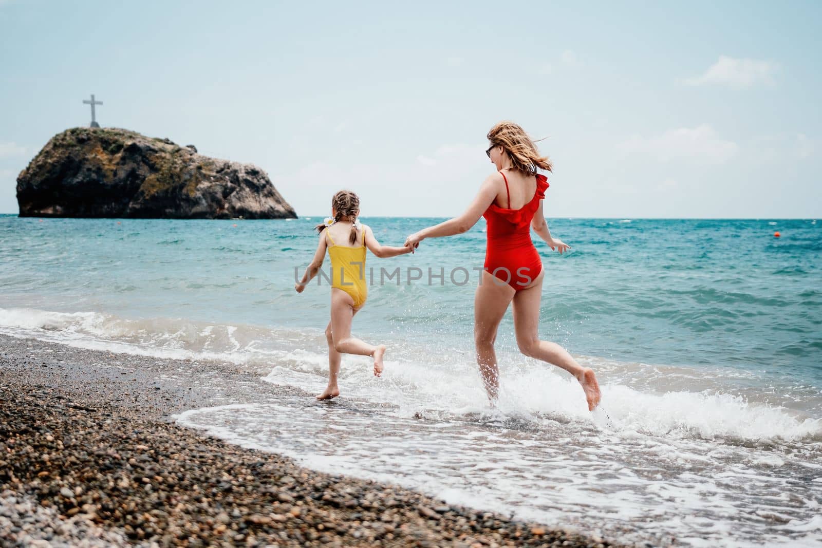 Happy loving family mother and daughter having fun together on the beach. Mum playing with her kid in holiday vacation next to the ocean - Family lifestyle and love concept by panophotograph