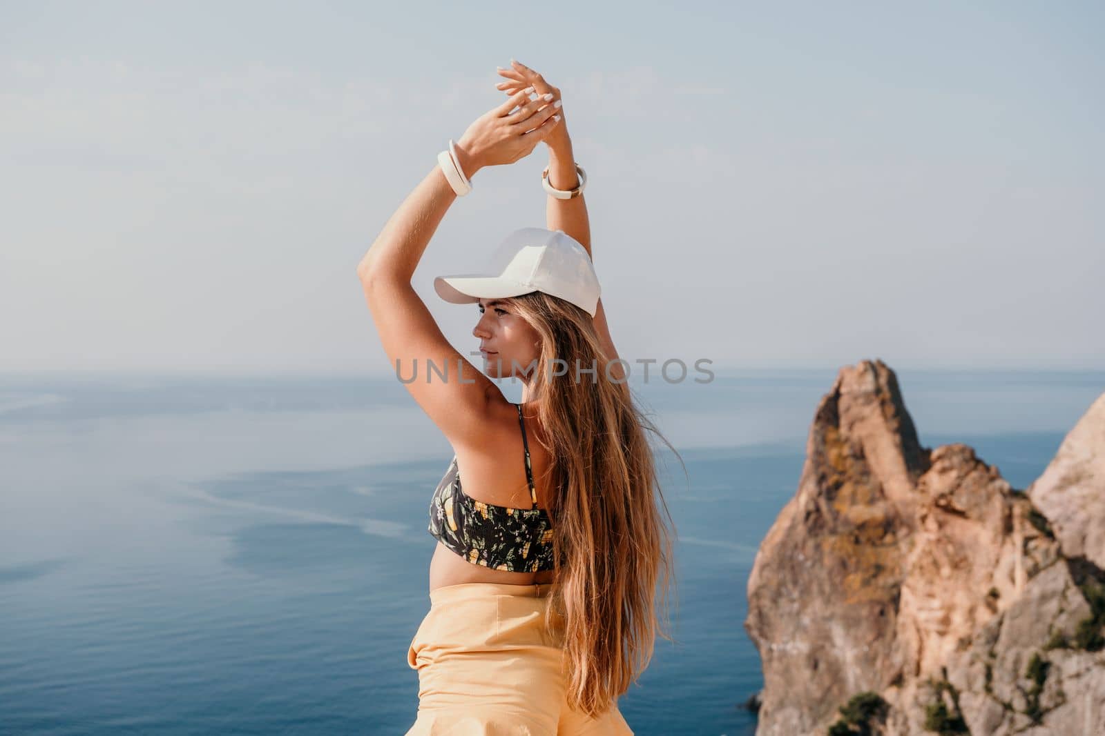 Woman travel sea. Happy tourist enjoy taking picture outdoors for memories. Woman traveler looks at the edge of the cliff on the sea bay of mountains, sharing travel adventure journey by panophotograph