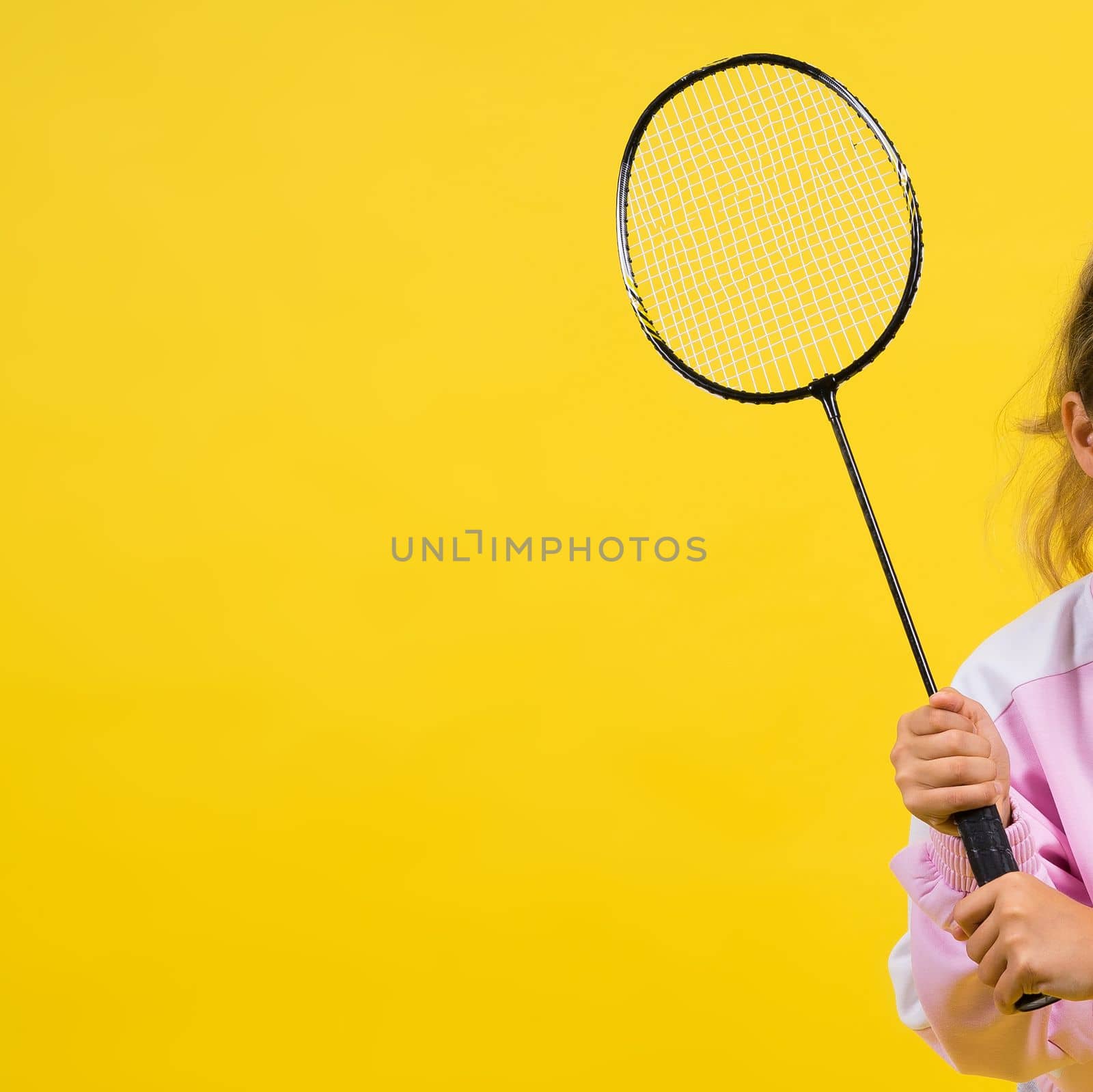 Full length studio photo of ten year old girl holding badminton racket and isolated on yellow. by Zelenin