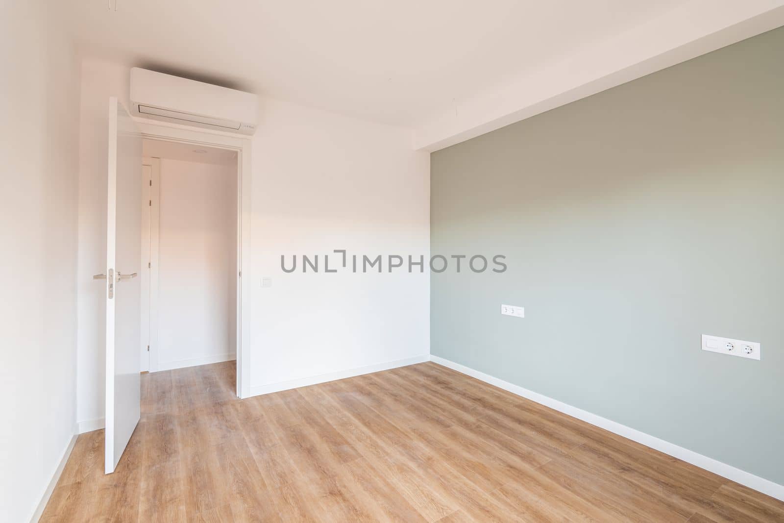 Bright spacious bedroom with parquet flooring. An open door from the room leading to a corridor with other rooms. Air conditioning above the door saves from summer heat by apavlin
