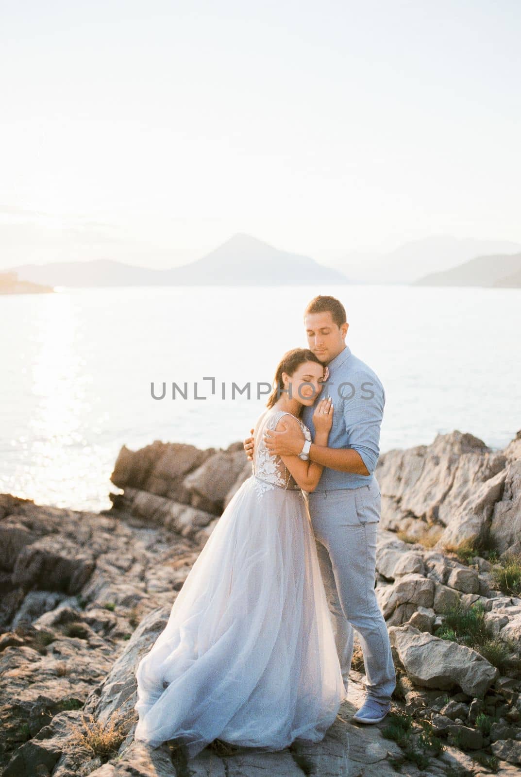Groom hugs bride on the stone coast by the sea. High quality photo