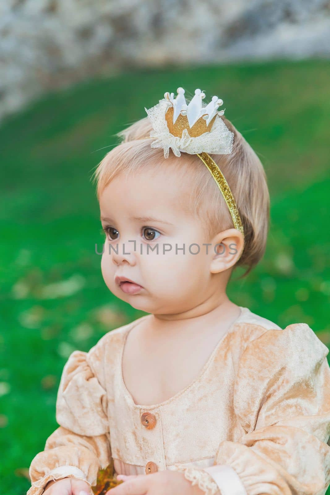 charming baby in princess costume walks near the castle at sunset.
