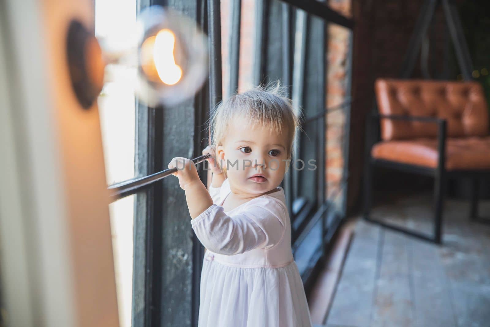 adorable newborn baby girl in dress near the window.