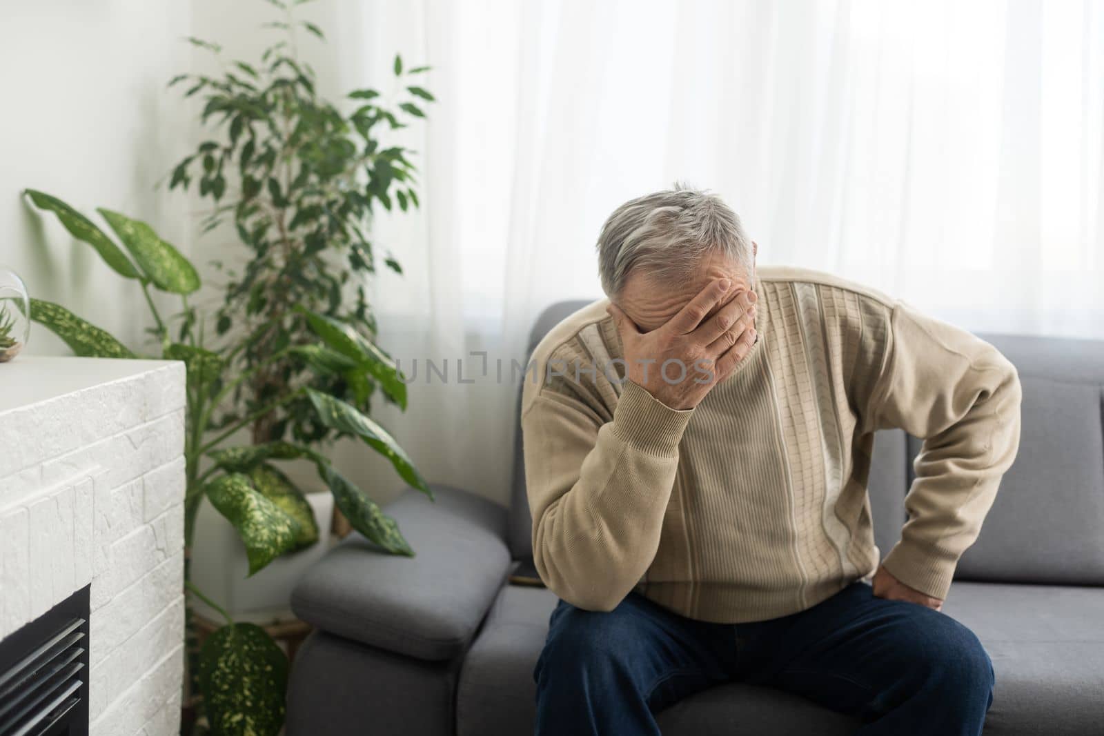 Tired old man suffering from headache, massaging his temples. Strong migraine attack. An elderly man has a headache, massaging his temples by Andelov13