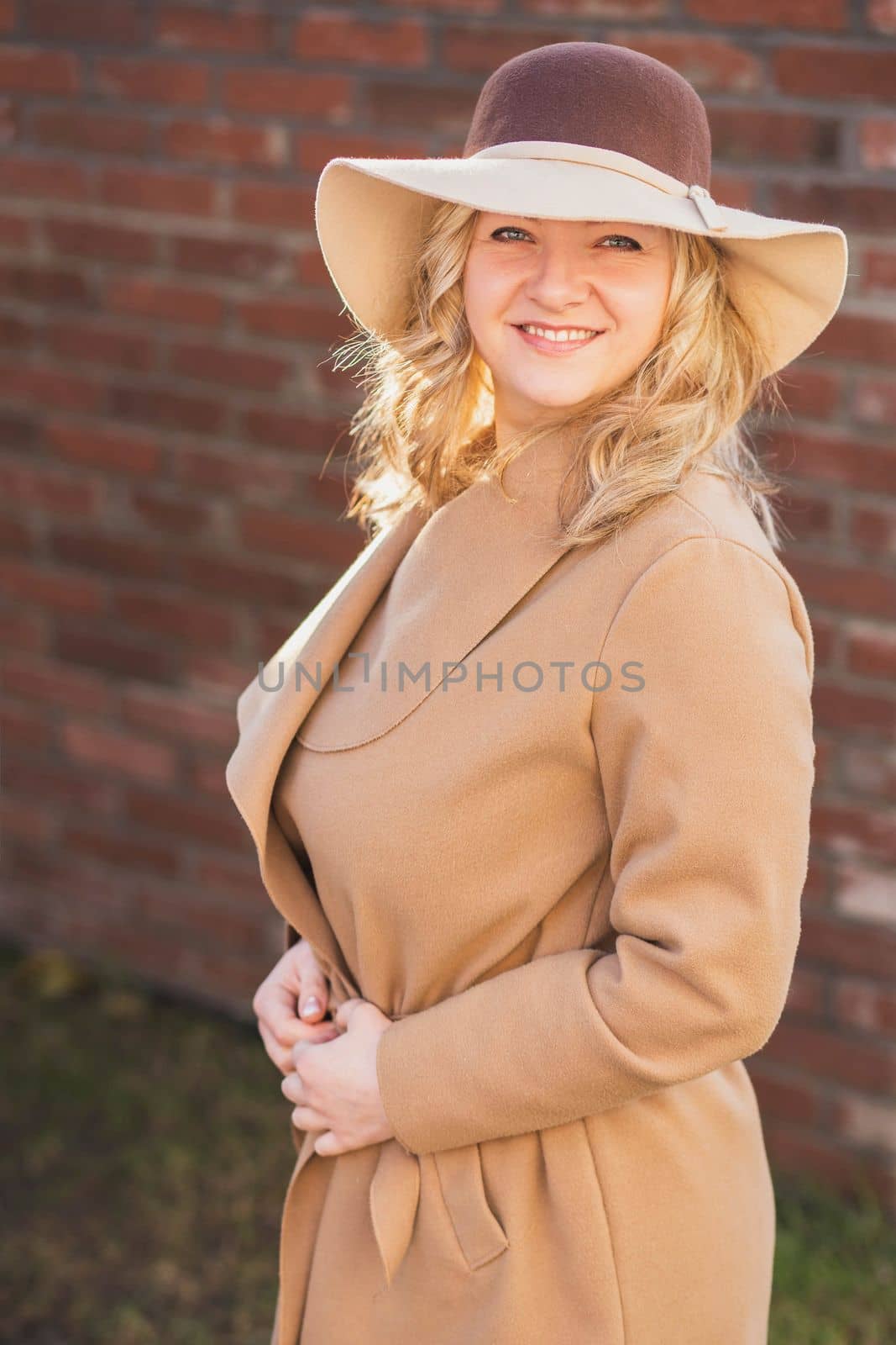 Elegant blonde woman in coat and hat.