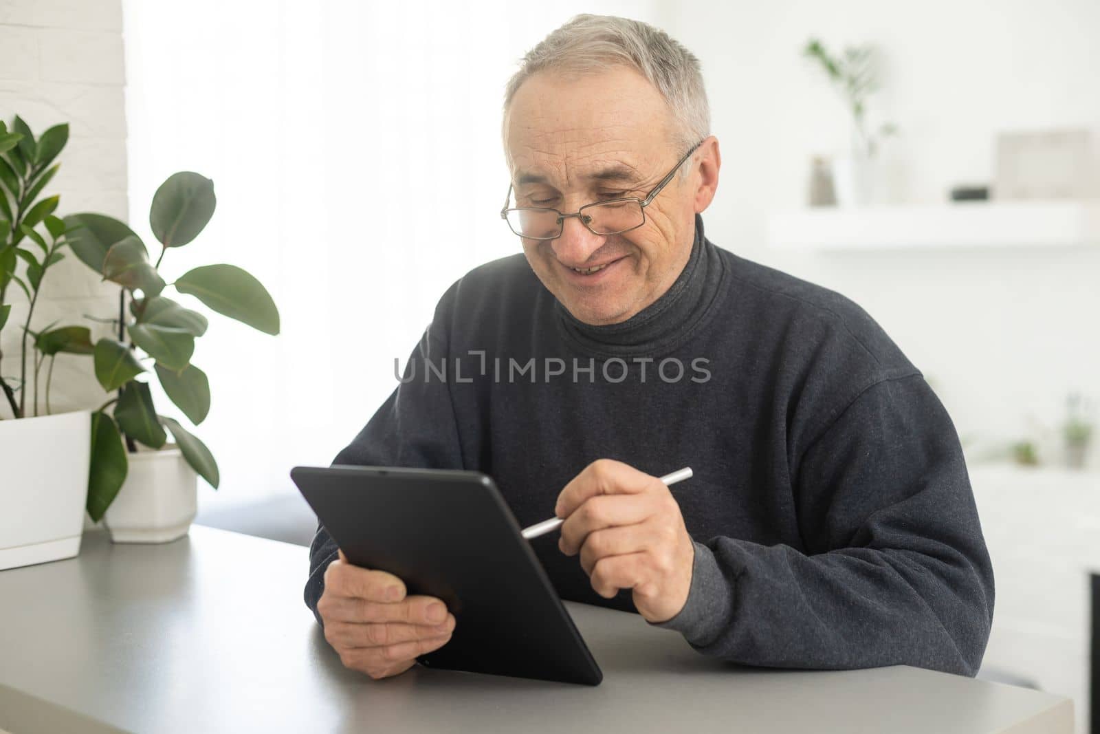 Senior man using tablet computer at home in the living room