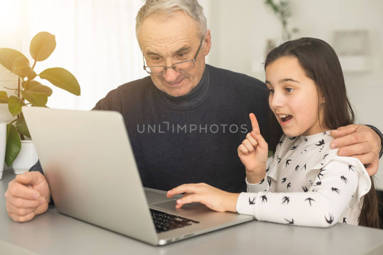 Grandfather and granddaughter spend time together use laptop, browse website, younger generation teach explain to older how to use modern tech concept by Andelov13