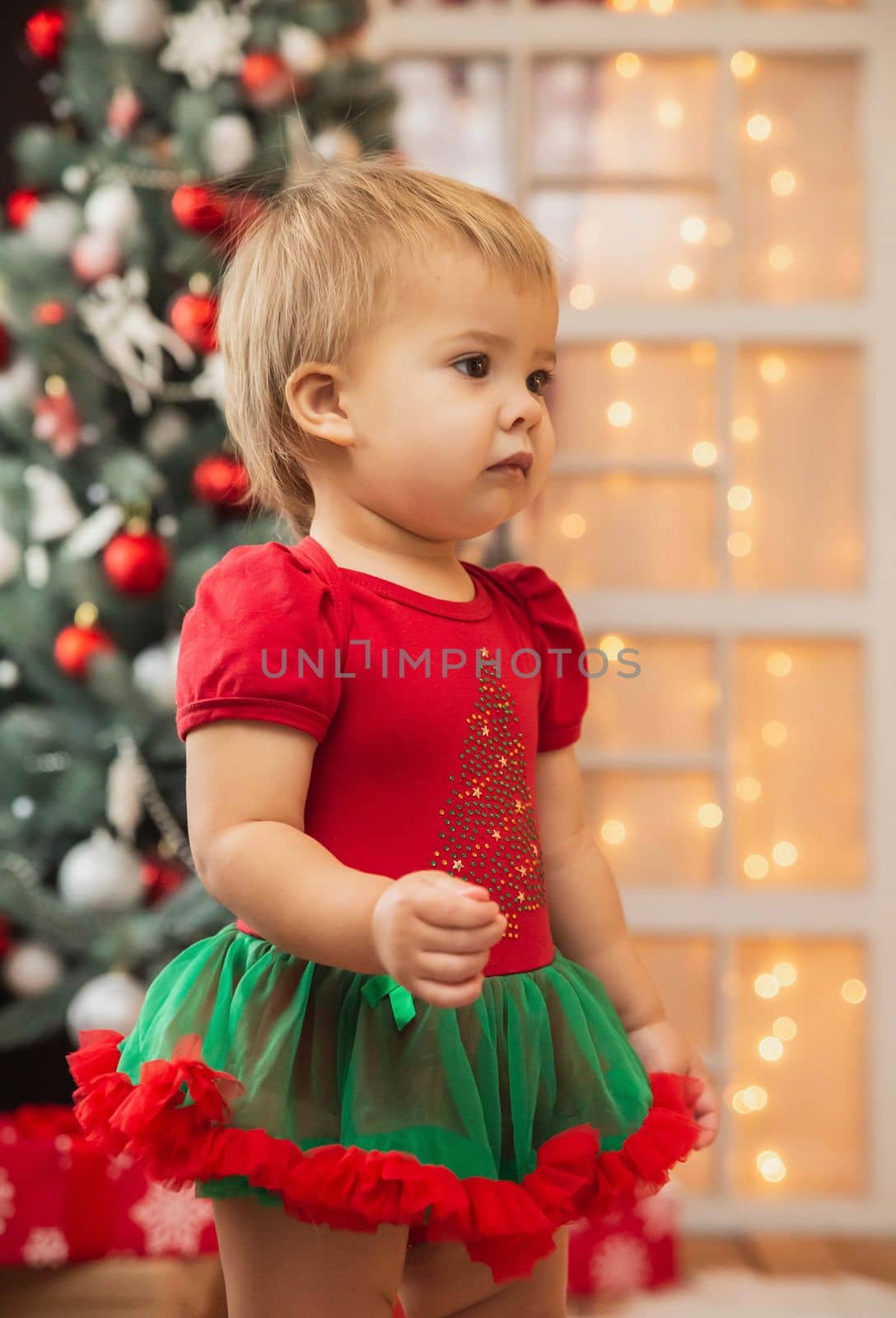 Beautiful baby in a New Year's suit. Christmas decorations.
