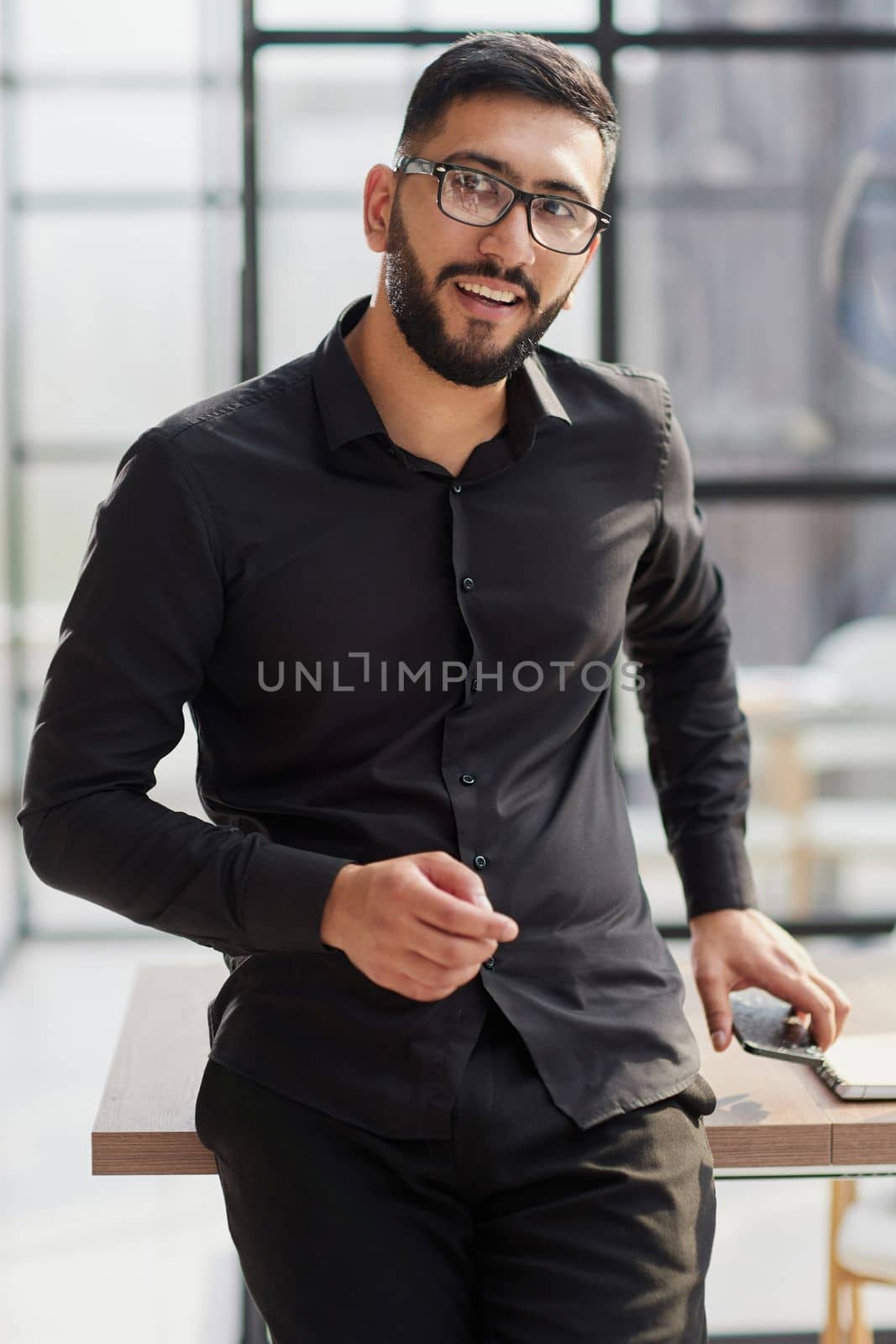 young businessman smiling in the office with his arms crossed