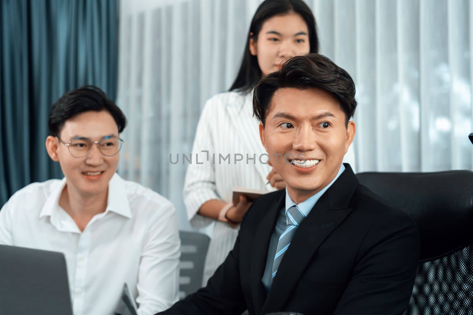 Portrait of focus young successful confident male manager, executive wearing business wear in harmony office arm crossed with blurred meeting background of colleagues, office worker.