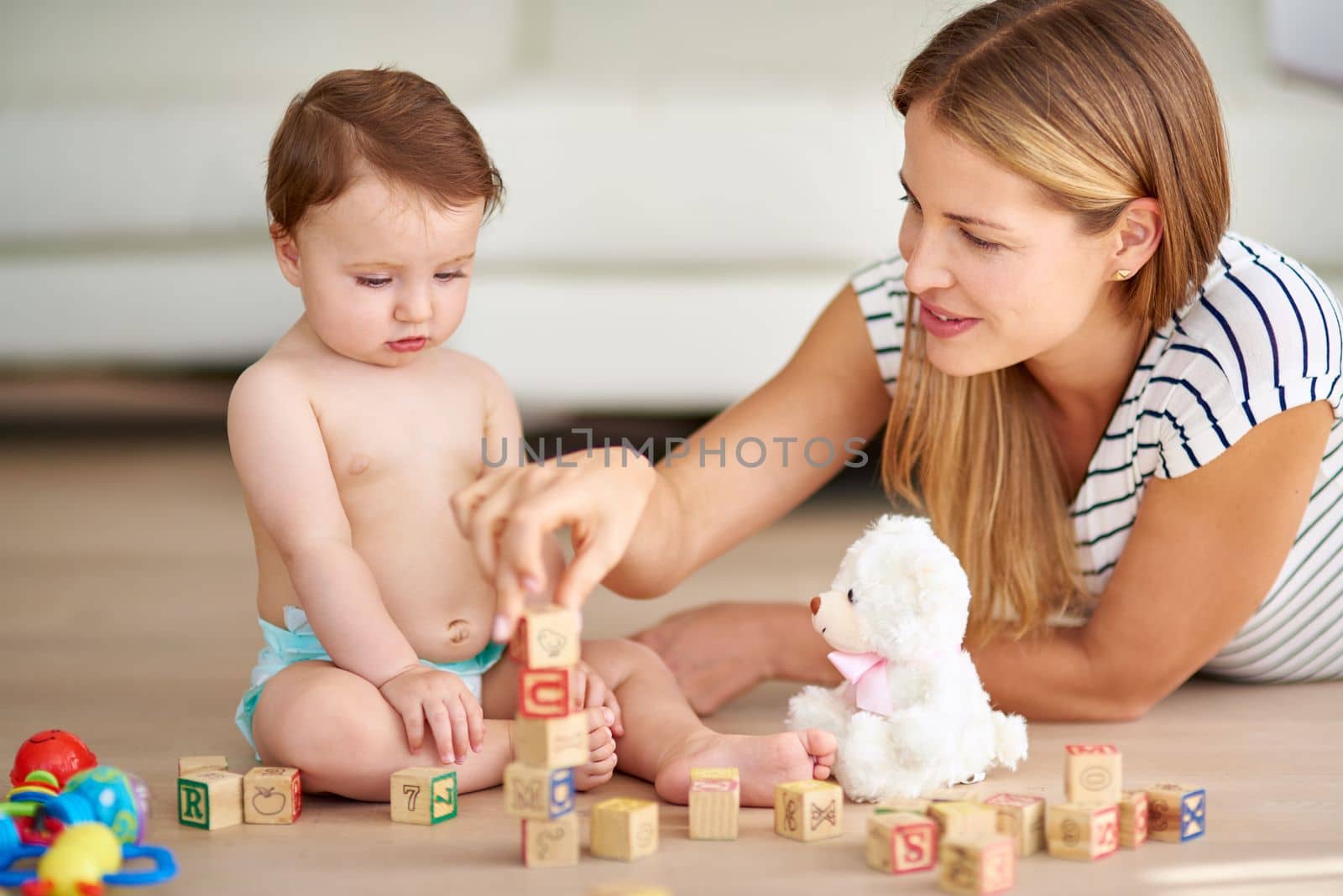 Growing and learning is childs play. an adorable baby girl and her mother playing with wooden blocks at home. by YuriArcurs