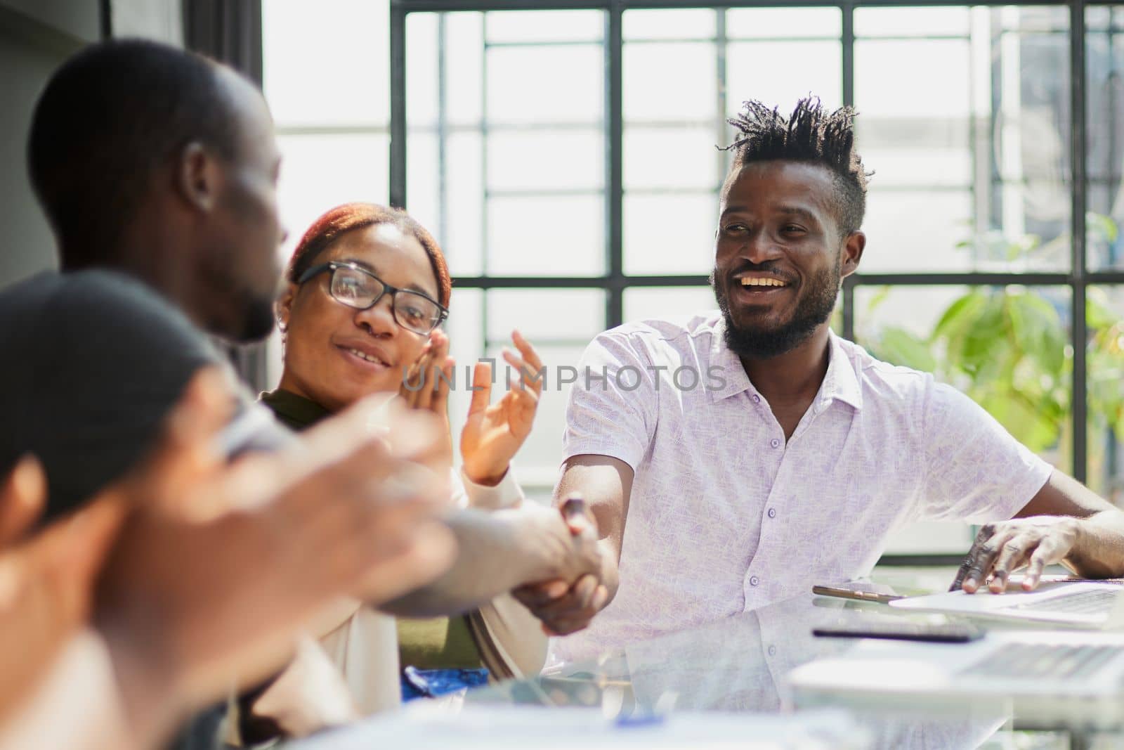 team of young african people in the office shaking hands