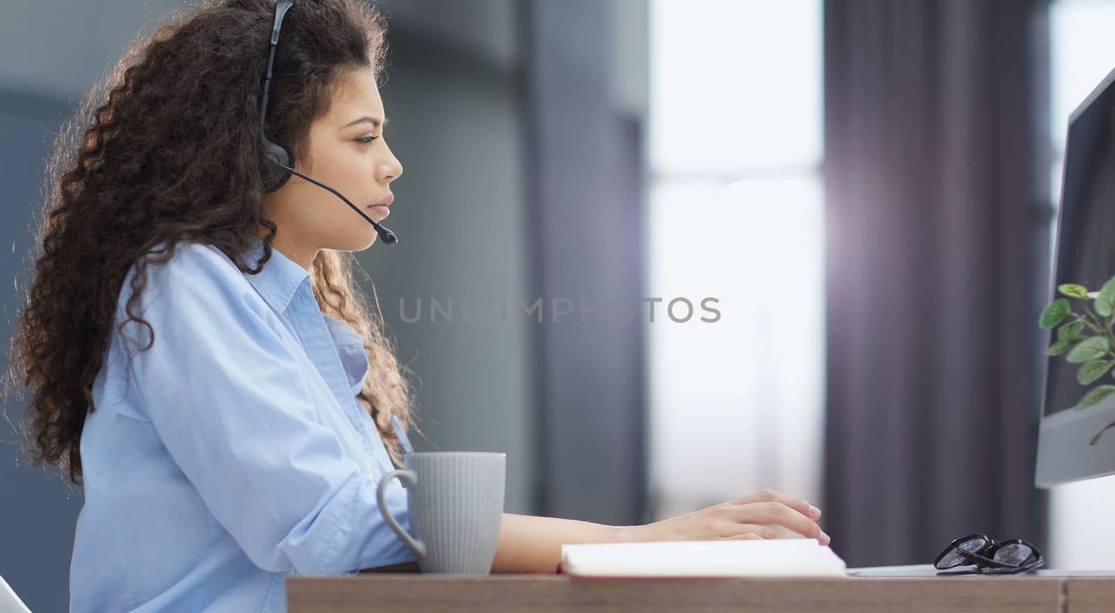 Side view of cheerful operator in headset in office
