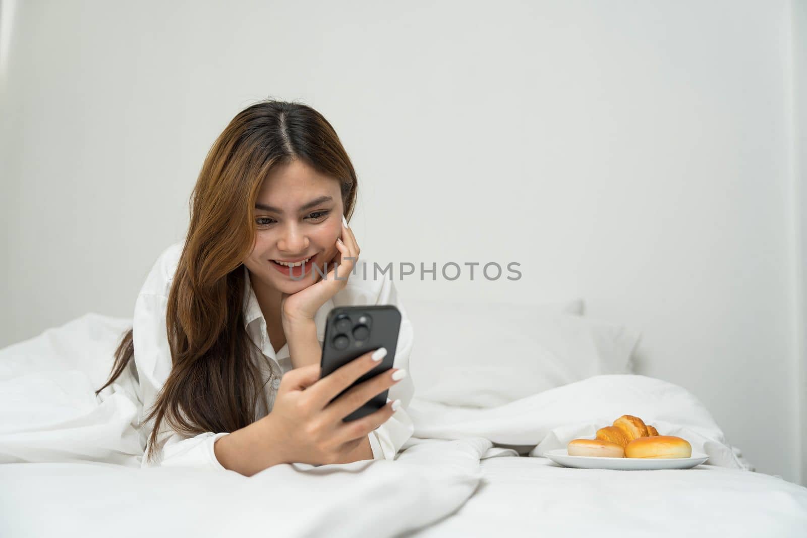 Beautiful young asian woman smiling sitting relax on the bed in the morning, girl using mobile smart phone talking enjoy, communication and social network concept...