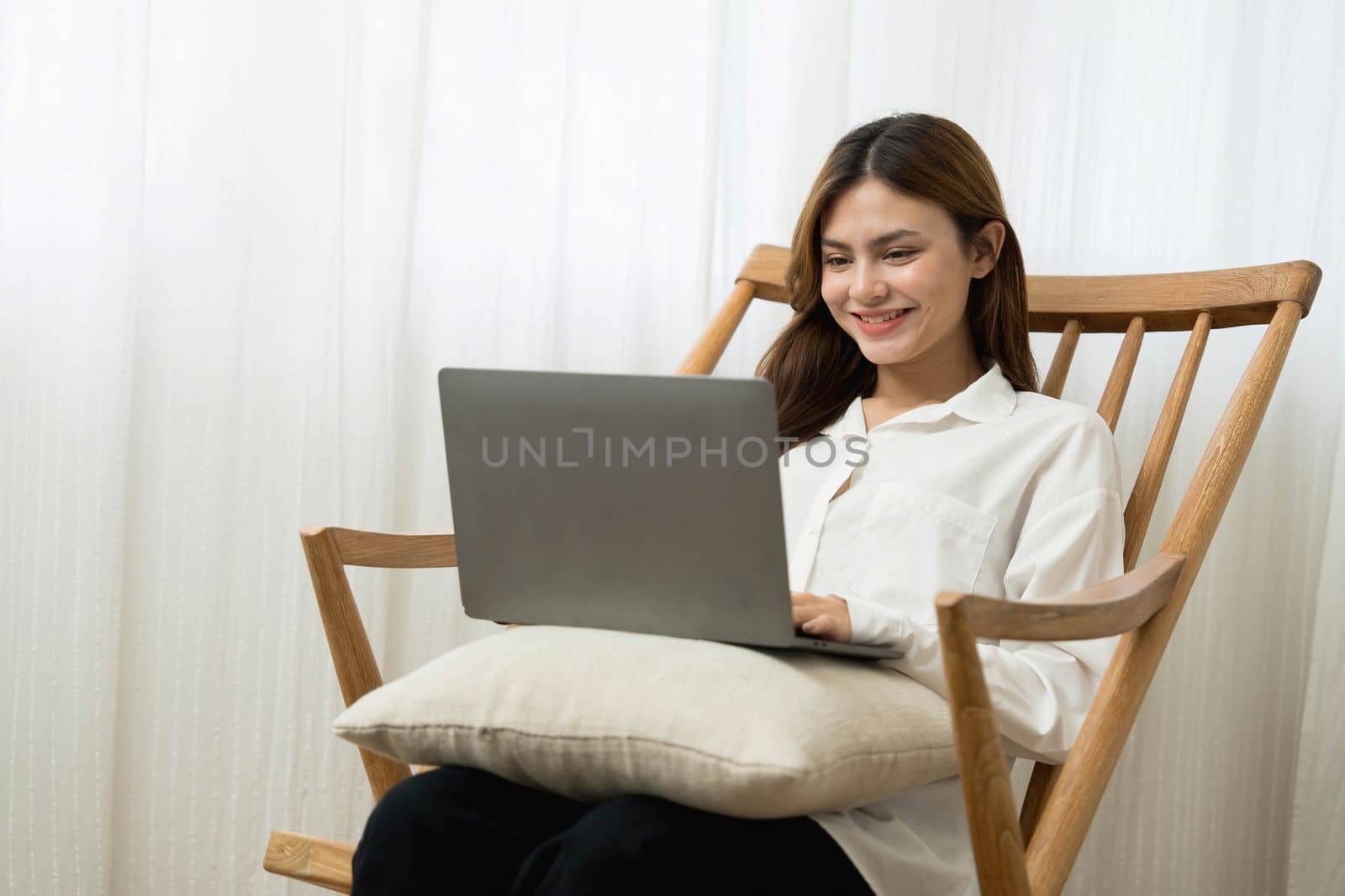 Young woman asian happy smiling celebrate. While her using laptop sitting on brown chair at liveroom.