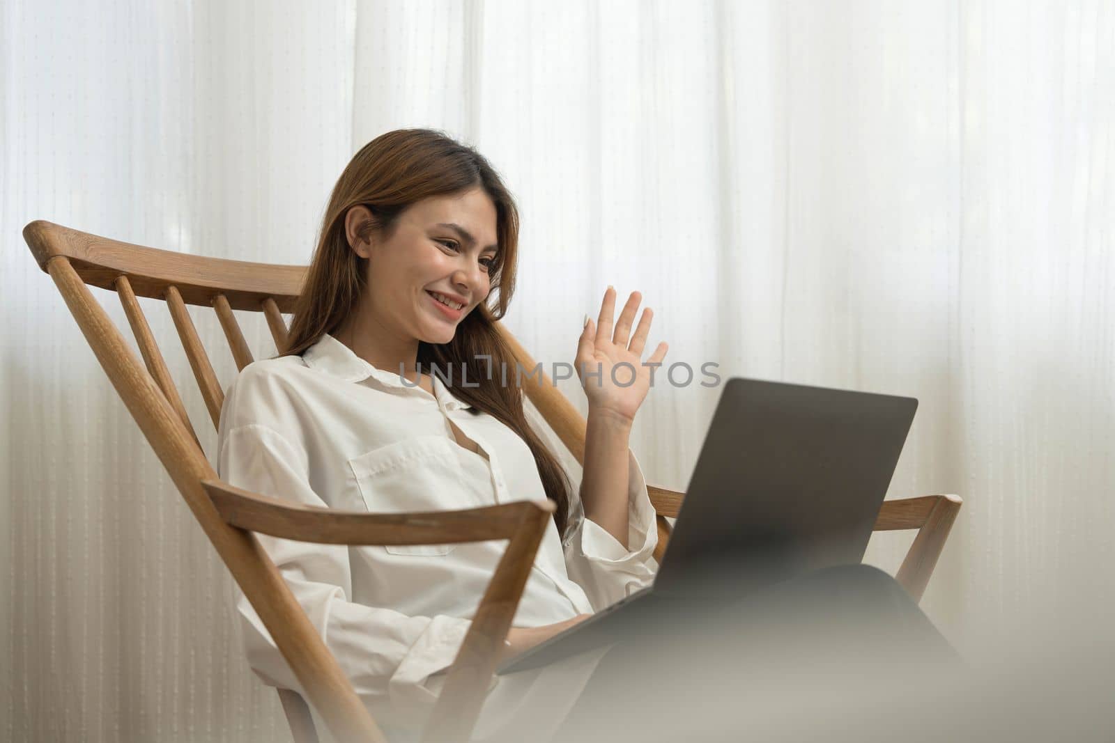 Young woman asian happy smiling celebrate. While her using laptop sitting on brown chair at liveroom.