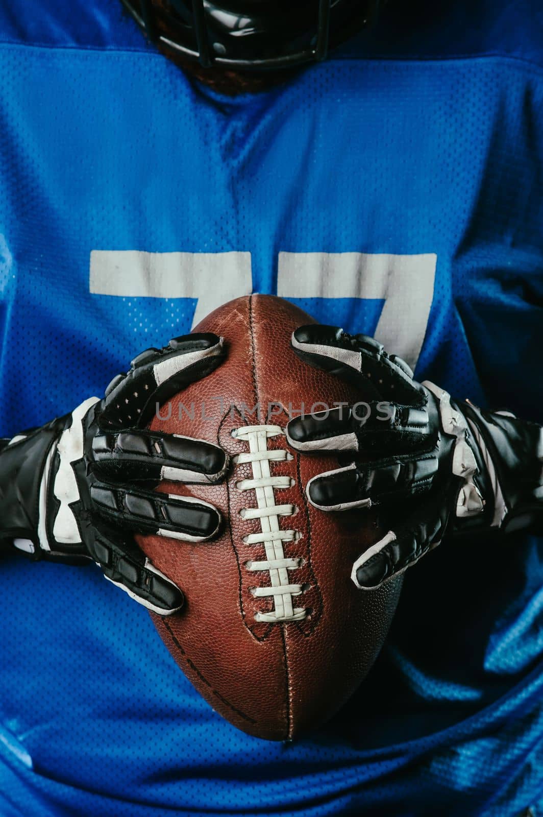 A close-up of an American football ball in the hands of a player