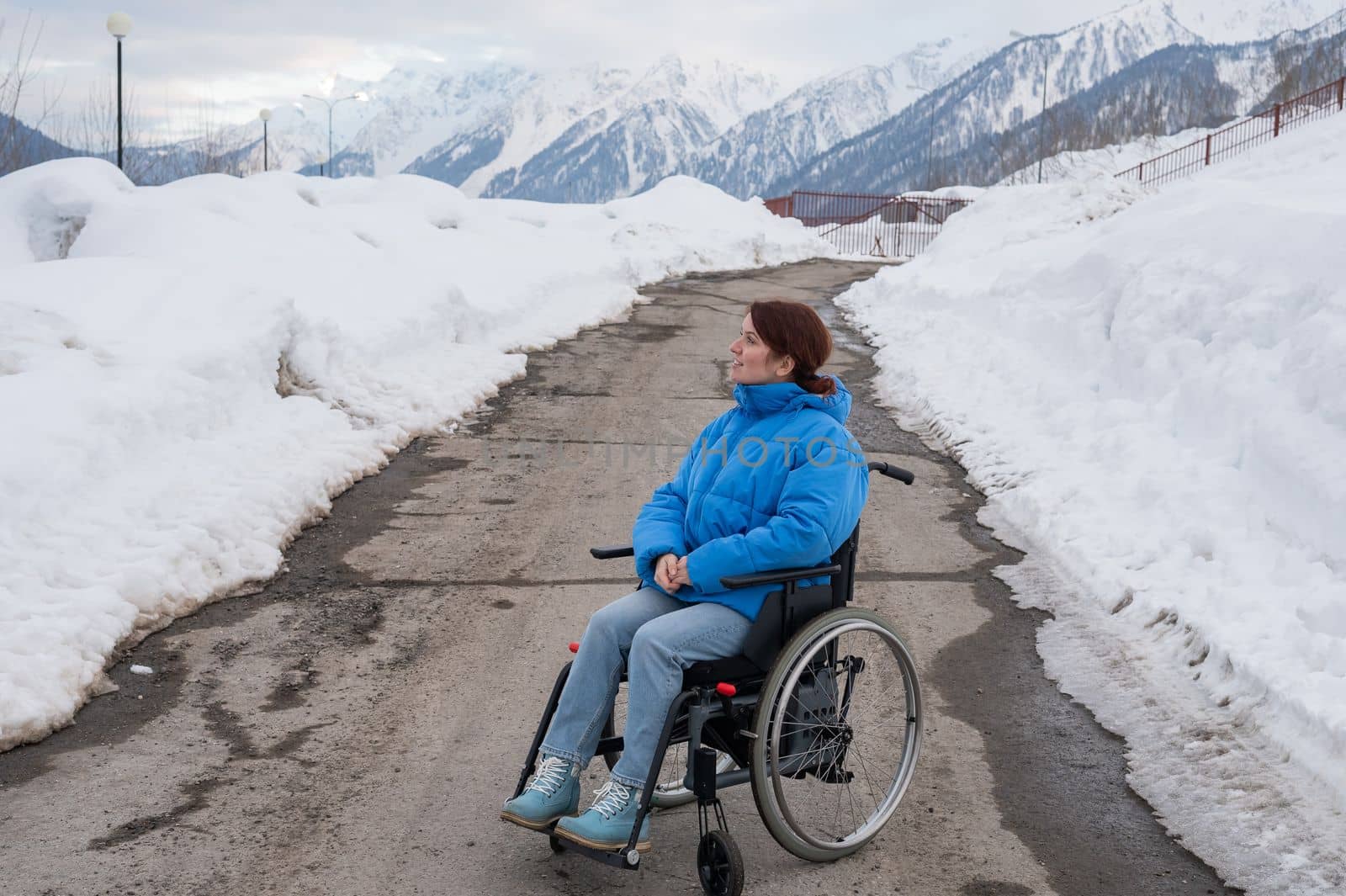 Caucasian woman in a wheelchair travels in the mountains in winter