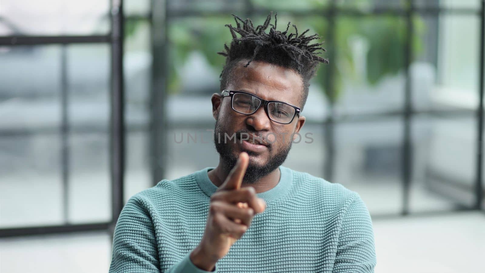 Portrait of a serious african american man, shaking his finger, warning and preventing you from something bad, looking at the camera with a worried expression.